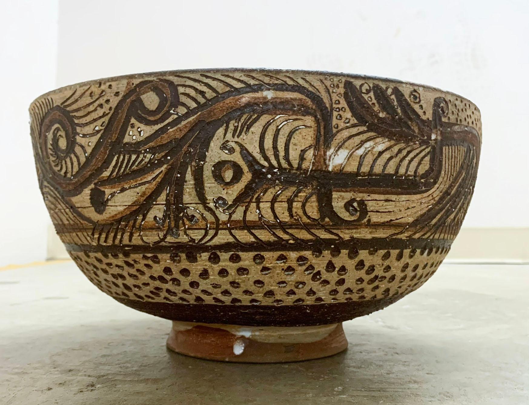 Eine mit Sgrafitto geschnitzte und mit Schlicker verzierte Aufsatzschale des am Bauhaus ausgebildeten Töpfers Frans Wildenhain. Es zeigt verschiedene phantastische Stammesfiguren und ein getupftes Punkteband in der Art eines afrikanischen