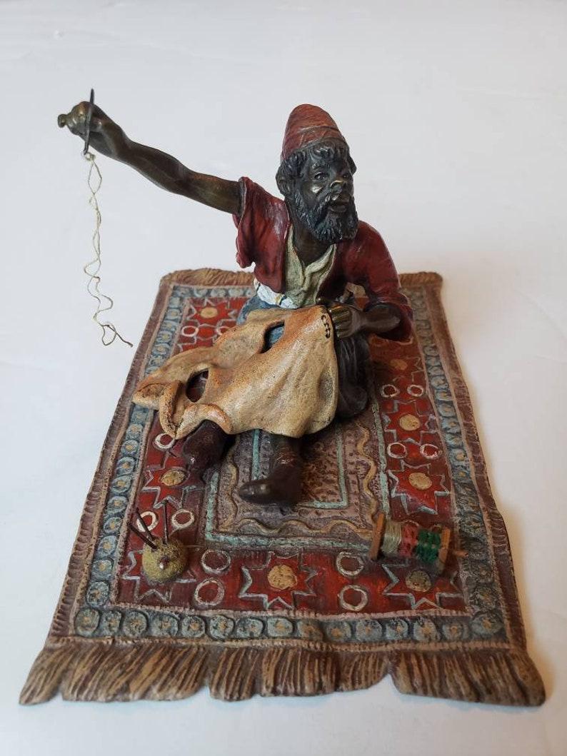 A highly coveted Franz Bergmann Vienna Cold Painted Bronze Figure of an Arab Tailor sewing on an alluring carpet of bold colors and patterns. One arm raised for holding the needle which still retains the original string. Skillfully crafted of heavy
