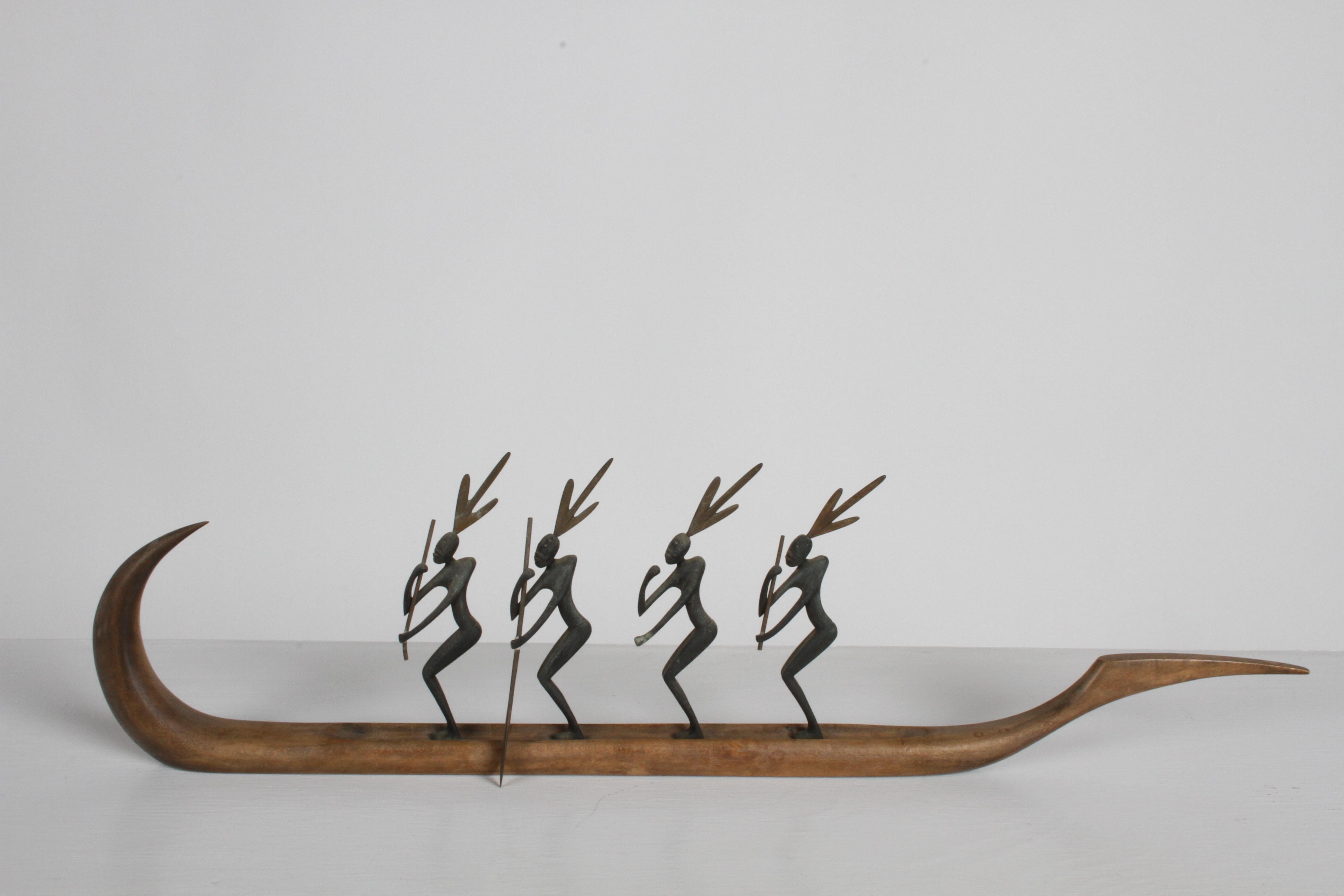 Karl Hagenauer sculpted wooden canoe with four bronze standing African paddlers with black patina, having bronze headdresses and bronze paddles. Bottom has stamped Handmade Hagenauer-Wien, circular WHW and made in Austria. Sold as-is with missing