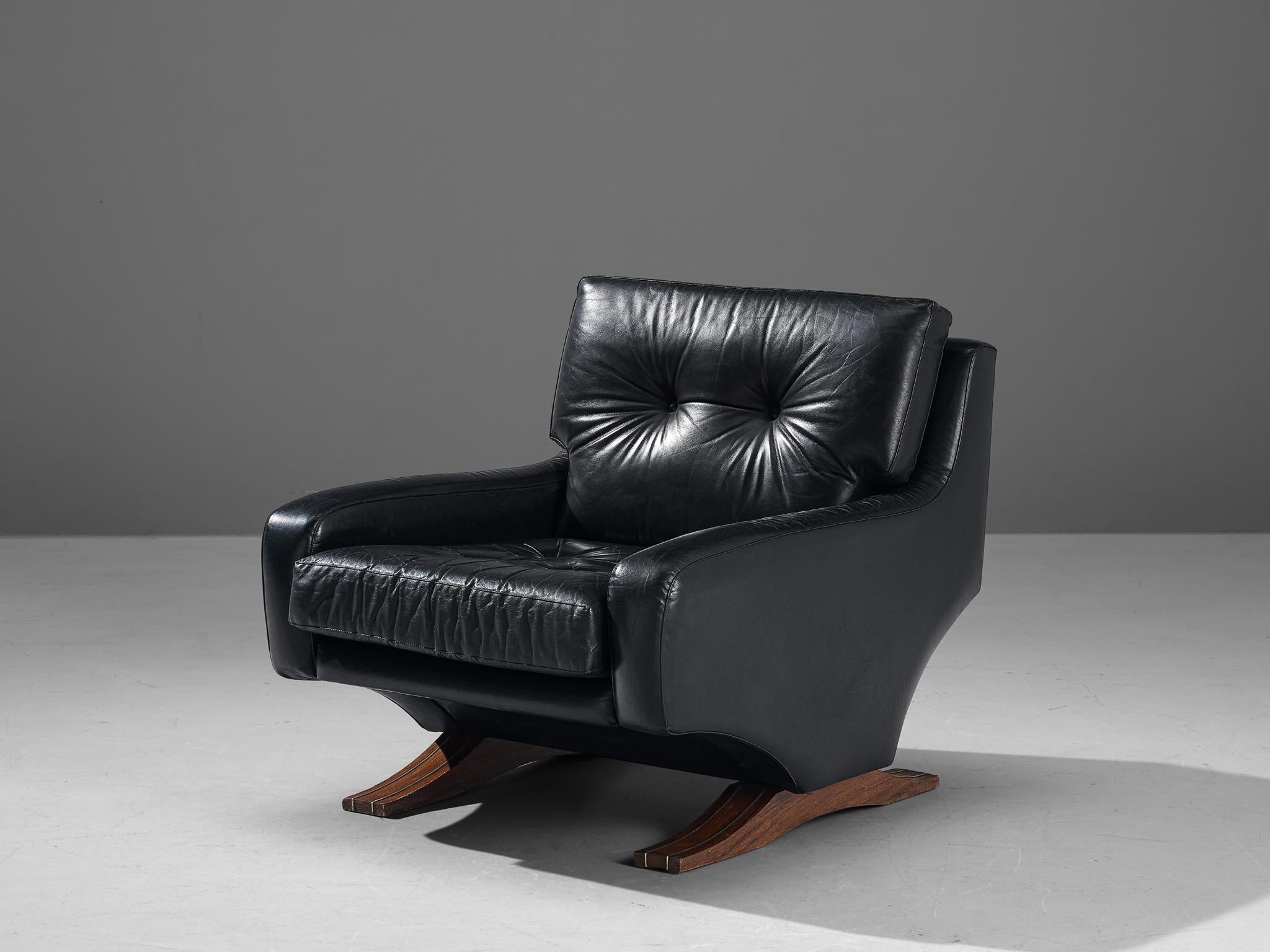 Franz Sartori for Flexform, lounge chair, leather, stained wood, metal, Italy, circa 1965.

This robust easy chair, designed by Italian sculptor Franz Sartori, stands as a testament to mid-century modern design. Enveloped in black leather, the