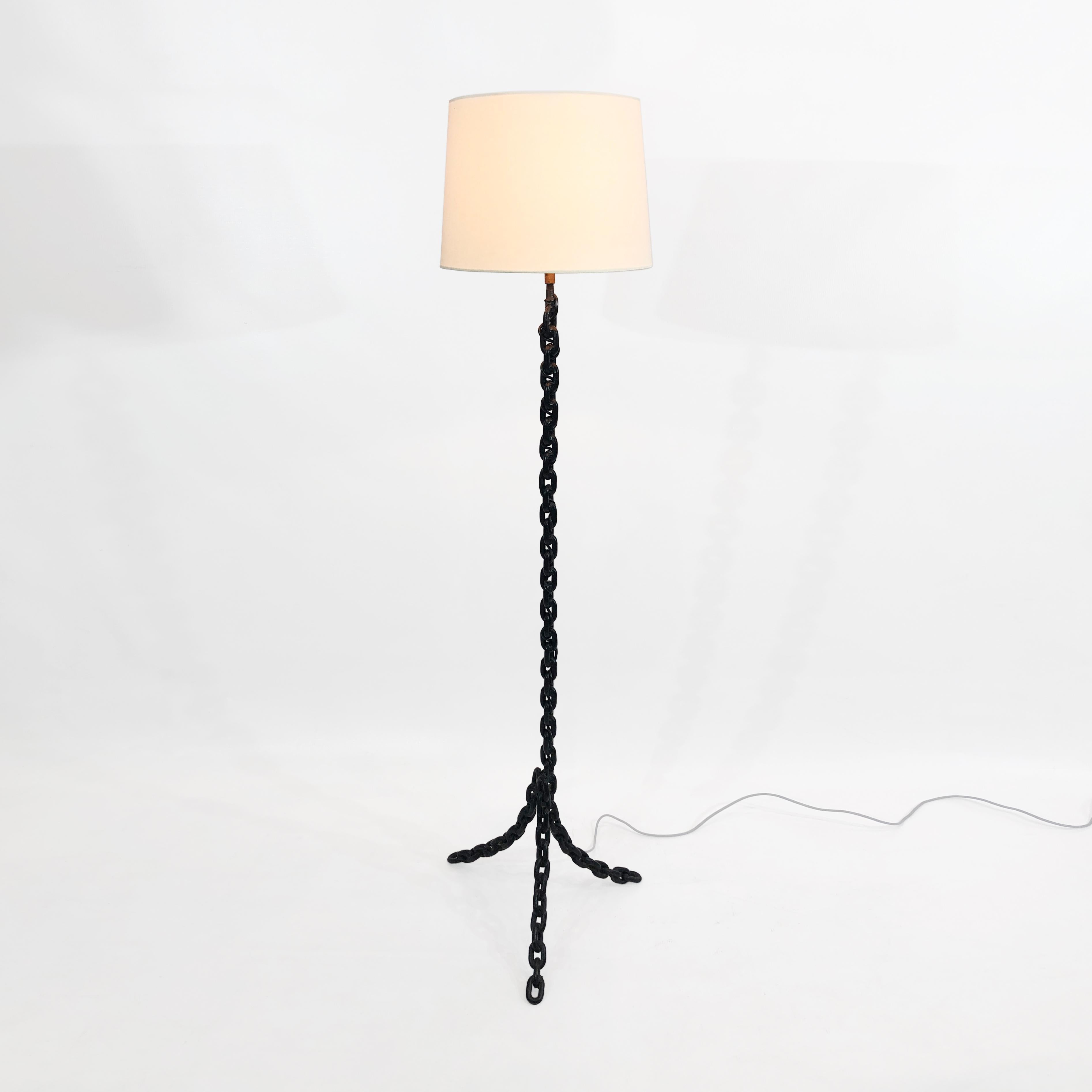 A tall chainlink floor lamp, reminiscent of the famous Privat Lampe des Künstlers II by legendary Austrian artist Franz West, that would be a striking addition to any home. Three forged iron legs converge into a central chain column, which leads up