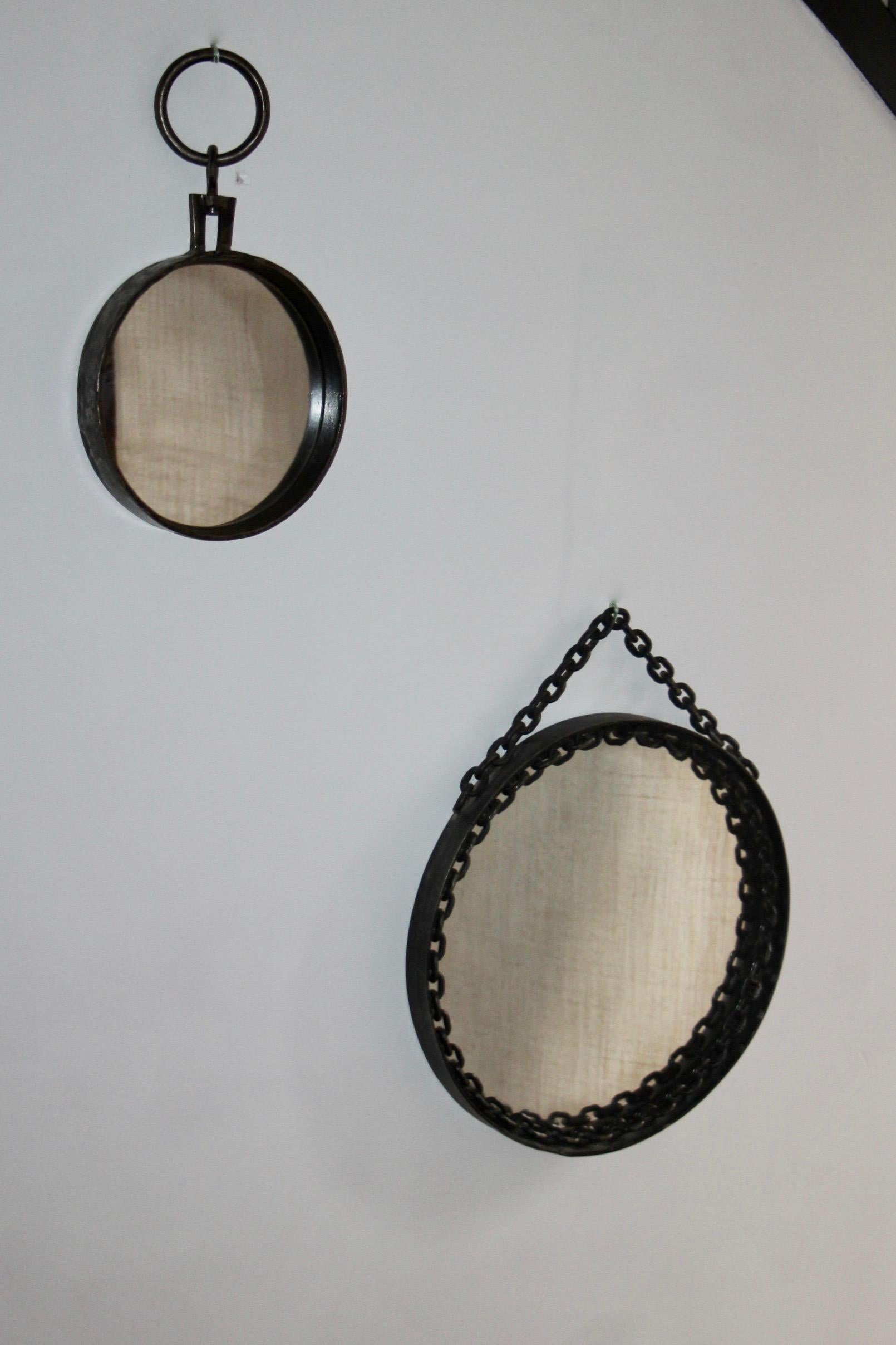 Franz West style round wall mirror in wrought iron.
Black and some silver color appearing as to give a slightly worn out creating a patina effect on the metal. 
The chain part is fixed around the mirror except for the upper part that is to be hung