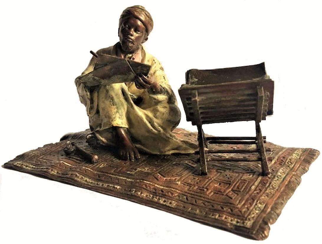 Diese wunderbare, lebensechte Skulptur stellt einen Koranschreiber dar, der mit angewinkelten Beinen Papierblätter in den Händen hält, auf denen er Verse aus dem Koran abschreibt, der vor ihm auf einem speziellen Ständer liegt. Zu seinen Füßen auf