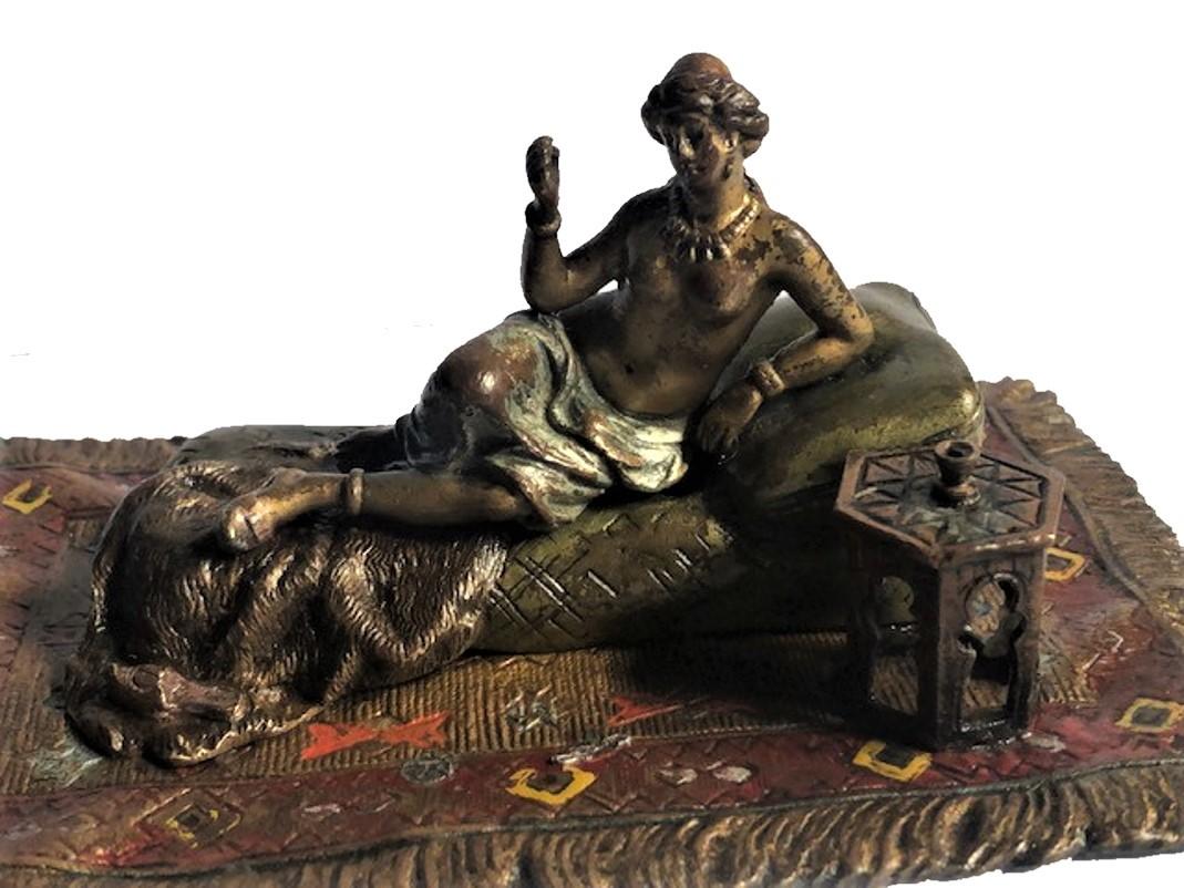 Cette merveilleuse sculpture grandeur nature représente une odalisque à moitié nue, allongée dans une pose paresseuse sur des oreillers en soie posés sur un ottoman, recouvert d'une peau de lion. Les seins nus, seul un petit foulard léger couvre la