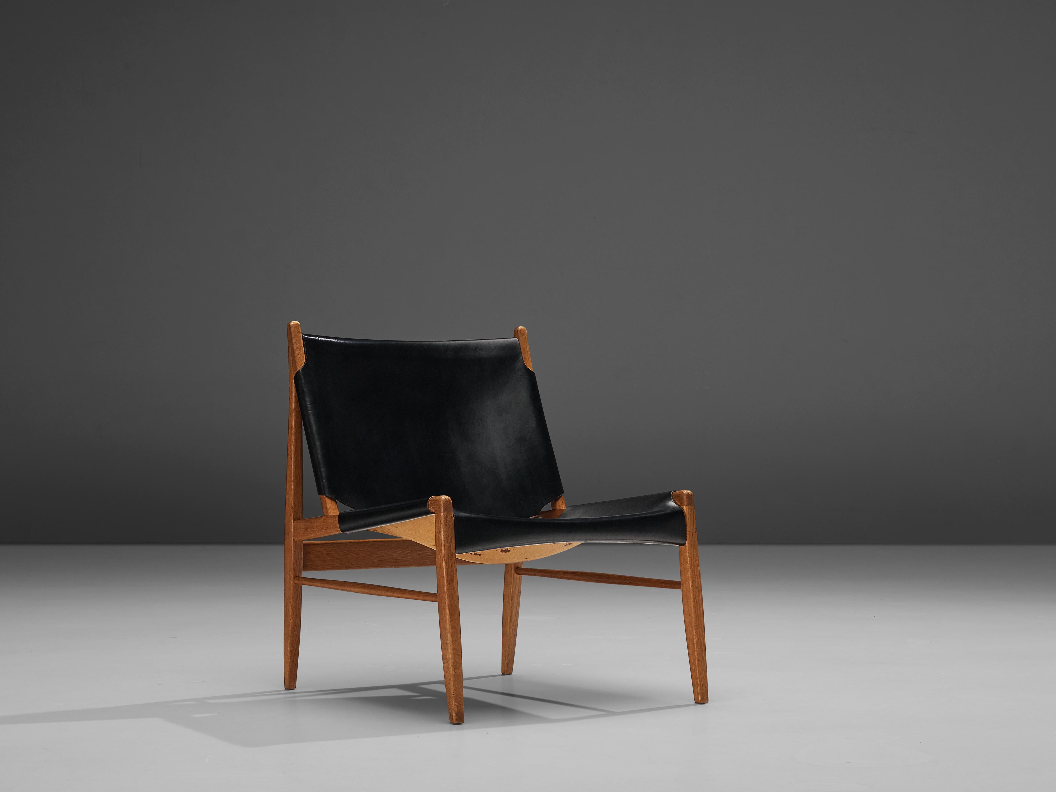 Franz Xaver Lutz for Deutsche Werkstätten, 'Chimney' chair model 1192, oak, original patinated black leather, Germany, 1958

This early 'chimney' chair is designed by Franz Xaver Lutz. The easy chair bears a strong resemblance to Spanish and