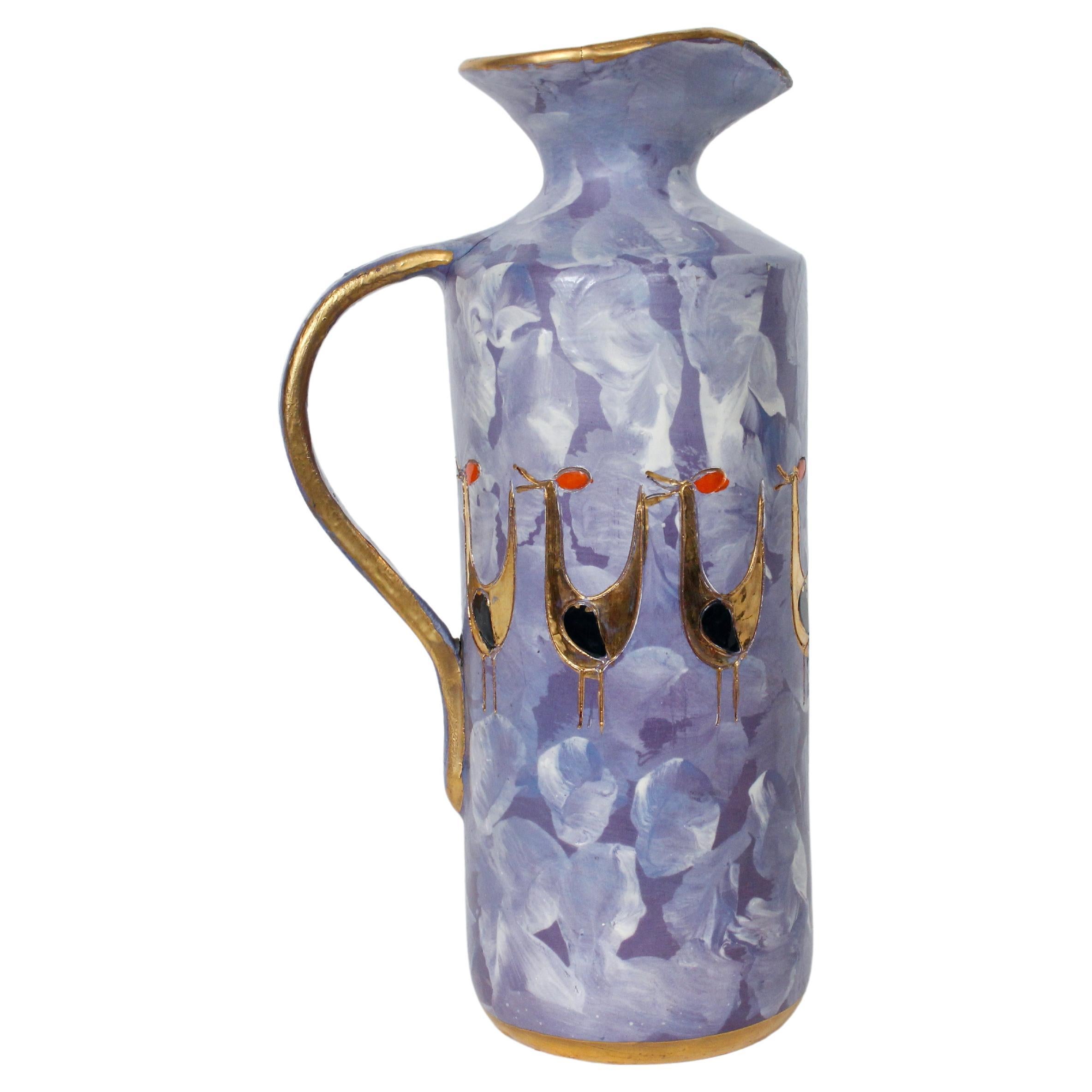 Sgraffito Purple Pottery Pitcher with Gilt Birds. Featuring a layered glazed ceramic Pale Purple toned handled Pitcher, Vase form, hand painted brushstrokes in Blues and White, Gilt rimmed lip, handle, and base, incised and painted sleek Gilt Birds