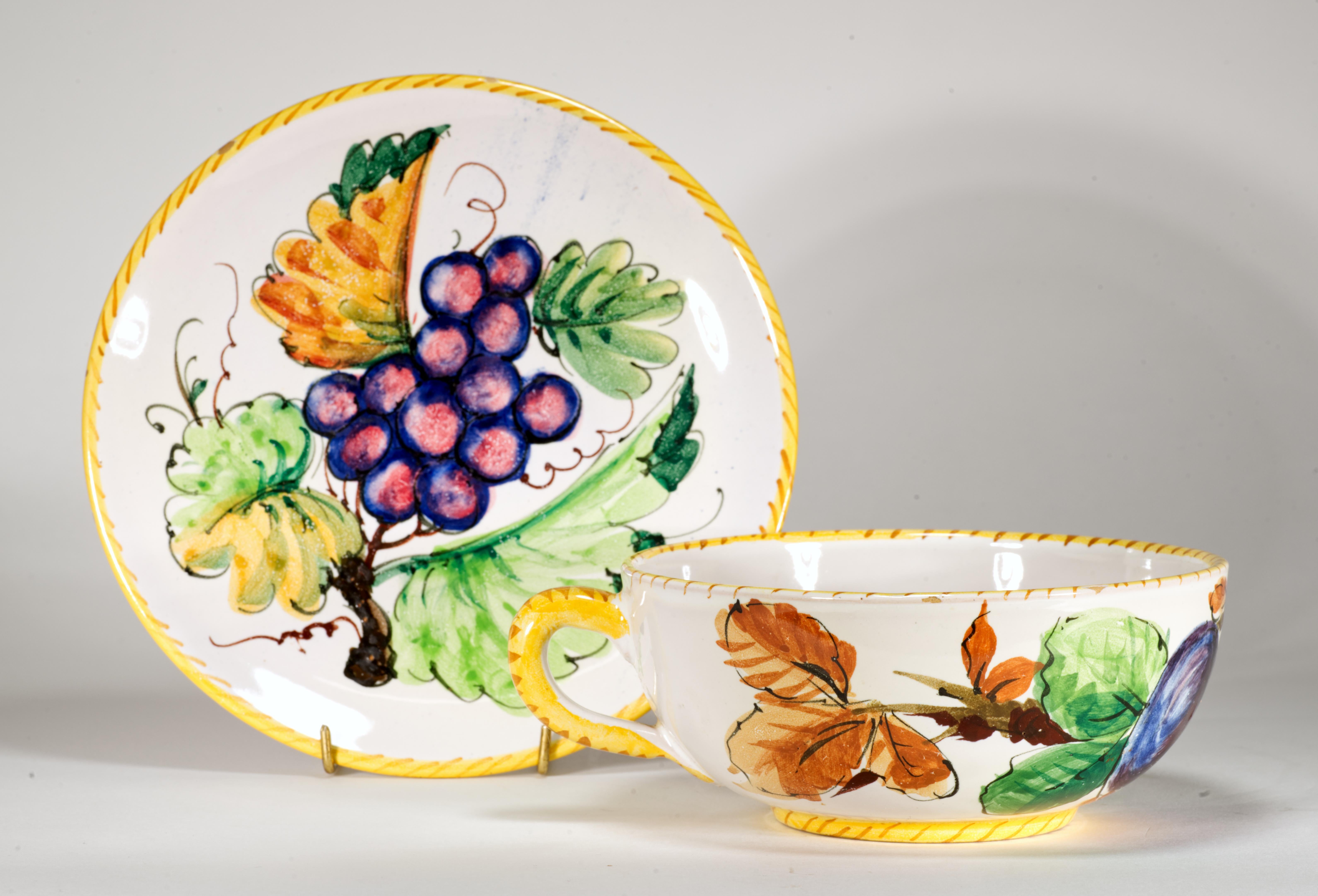  Raro juego vintage de taza y platillo de gran tamaño, decorado con frutas y hojas estilizadas pintadas a mano. En el platillo hay uvas, y en la taza, ciruelas; las frutas se representan colgando de ramas, rodeadas de hojas. Los bordes de la taza y