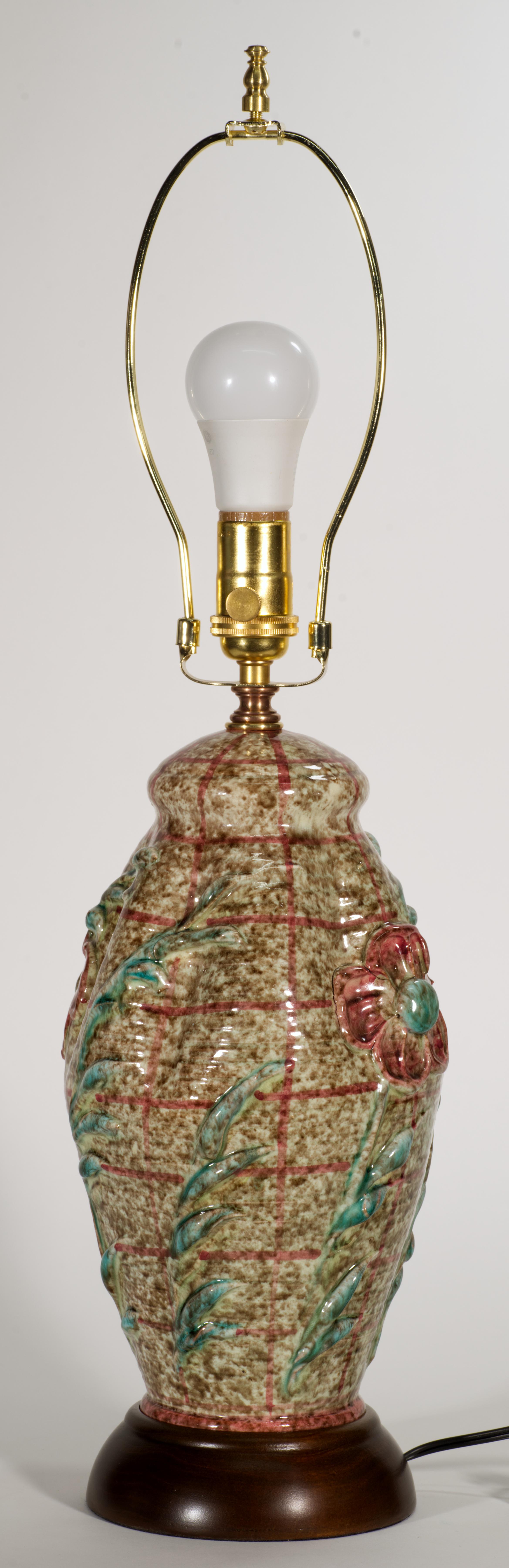  Seltene, ungewöhnliche Vintage-Majolika-Lampe mit abstraktem grafischem Dekor mit großen, reliefierten Blumenmotiven; der Korpus ist auf einem gedrechselten Massivholzsockel montiert. Der obere Teil des urnenförmigen Keramikkörpers wird durch 6