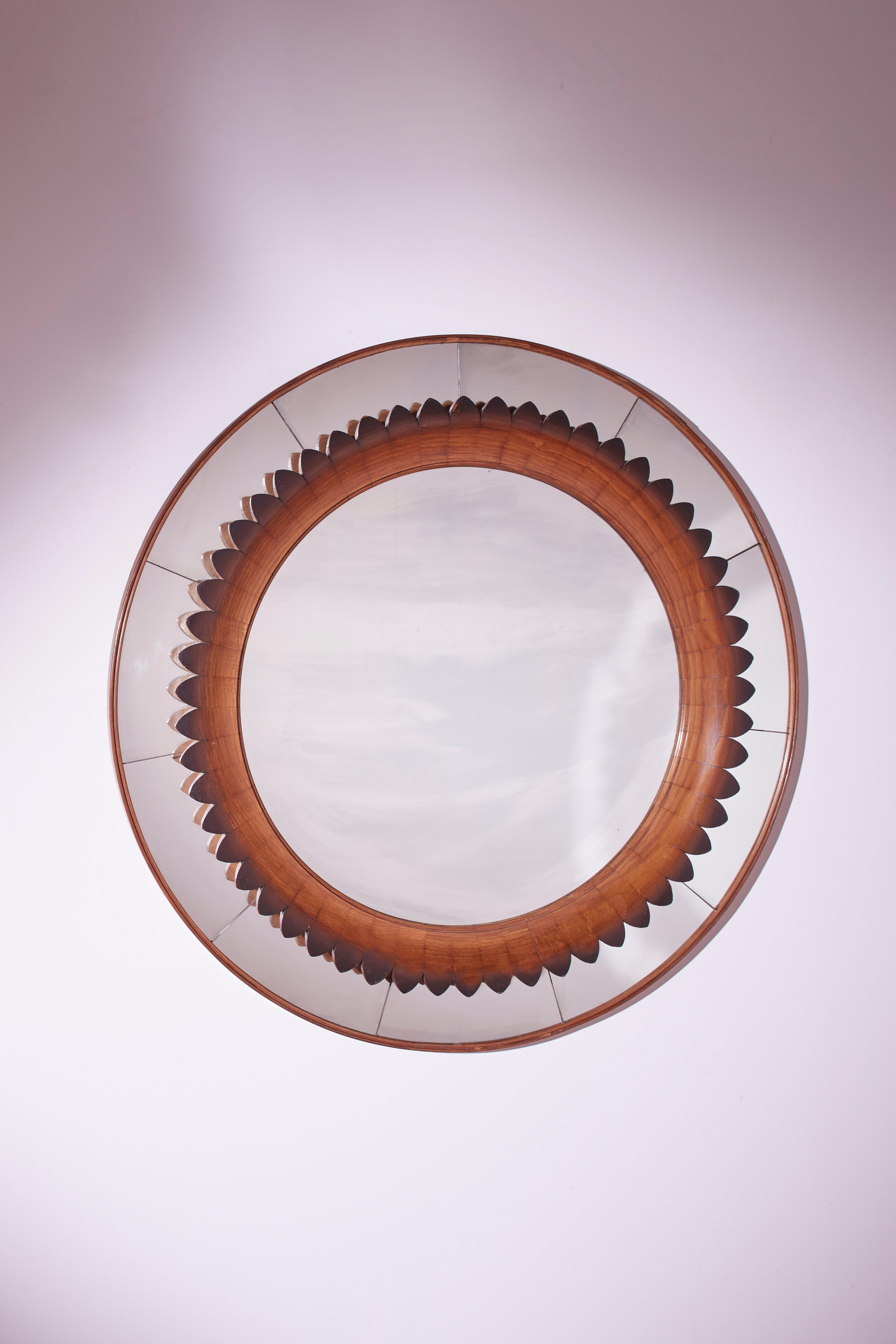 A beautiful round mirror framed in walnut wood represents the Italian craftsmanship mastery of the Fratelli Marelli from the 1950s. The modular wooden inserts that make up the frame evoke the image of flower petals or sun rays.

The mirror, always a