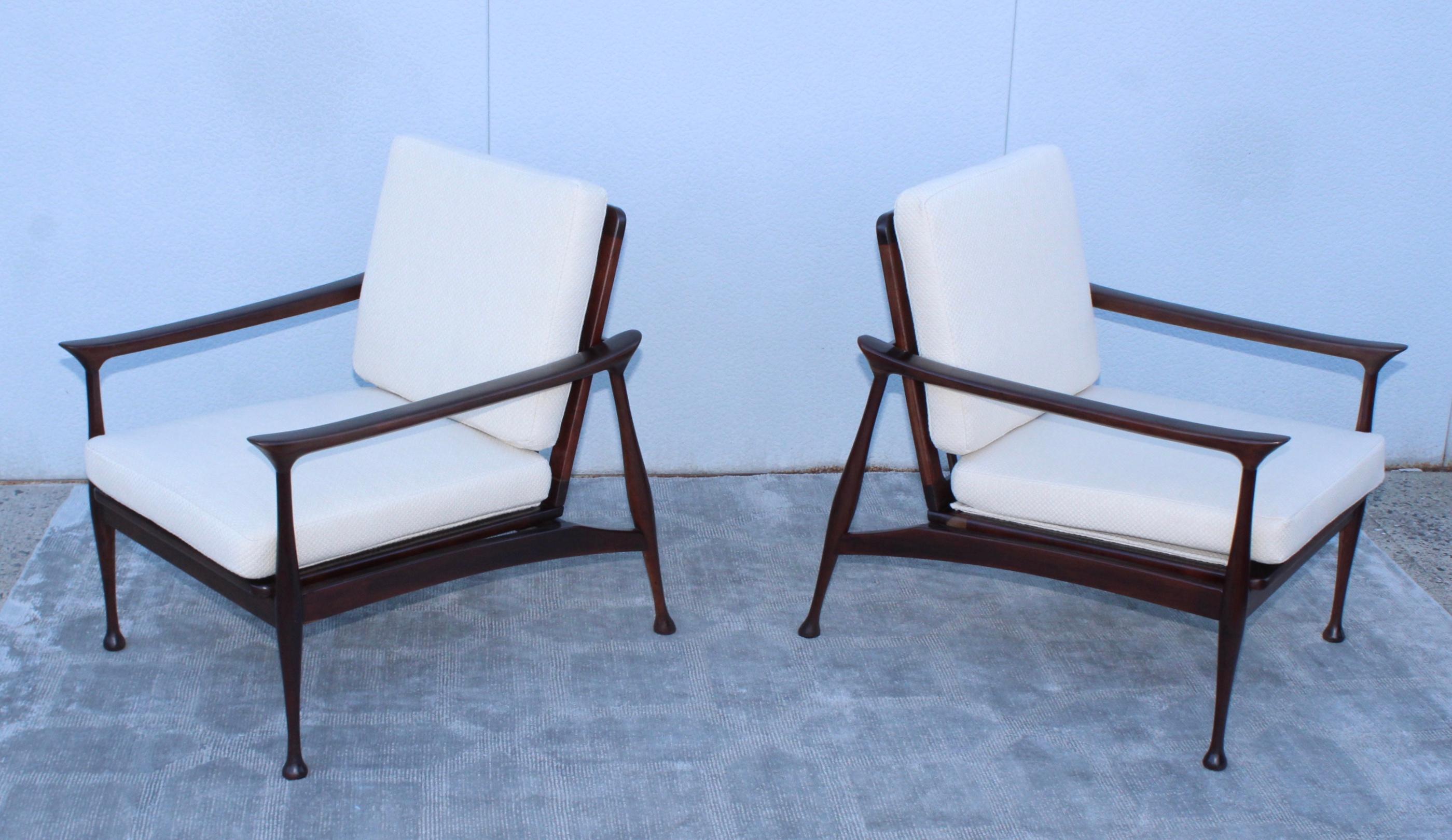 Stunning pair of 1950s Mid-Century Modern Italian walnut lounge chairs attributed to Fratelli Reguitti, lightly restored with new off-white upholstery, with some wear and patina to the wood minor repairs.