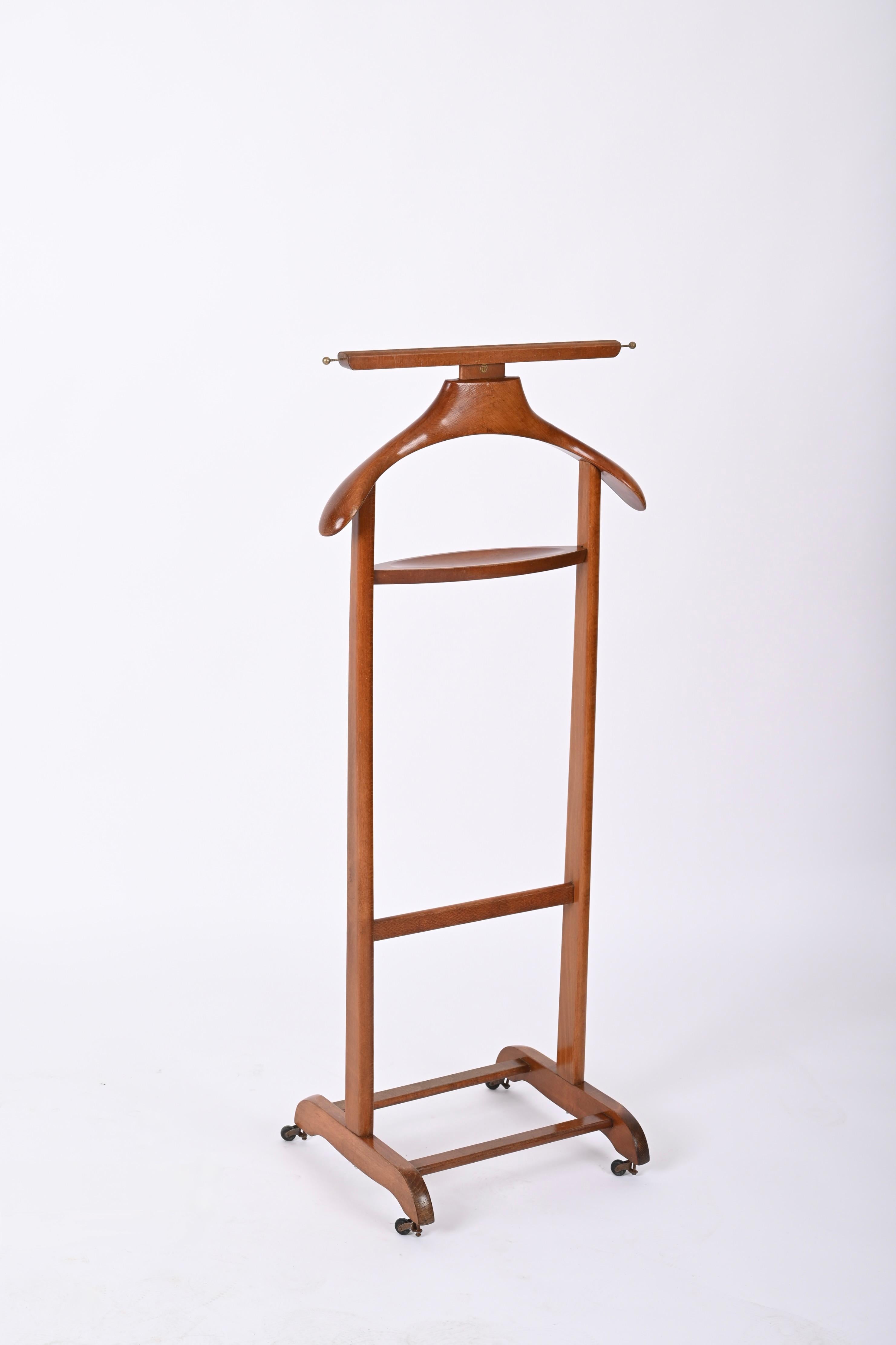 Very rare midcentury valet stand in beech and brass. This gorgeous item was produced during the 1950s by the Reguitti Brothers in Italy.

This unique coat rack is made of beechwood and features two solid brass hooks for belts or ties. The contrast
