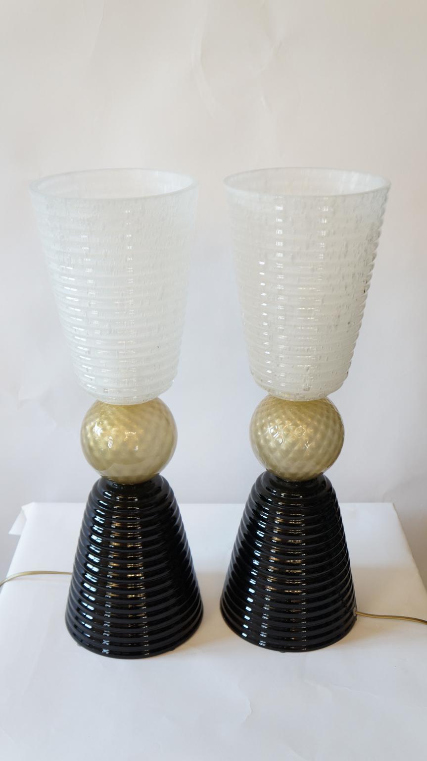 The lamp you can see in the picture is very simple but impressive. It is precisely the striking complementarity
between black and white, divided by gold leaf 24-karat, that makes it so elegant. 
It develops with two symmetrical cups divided by a