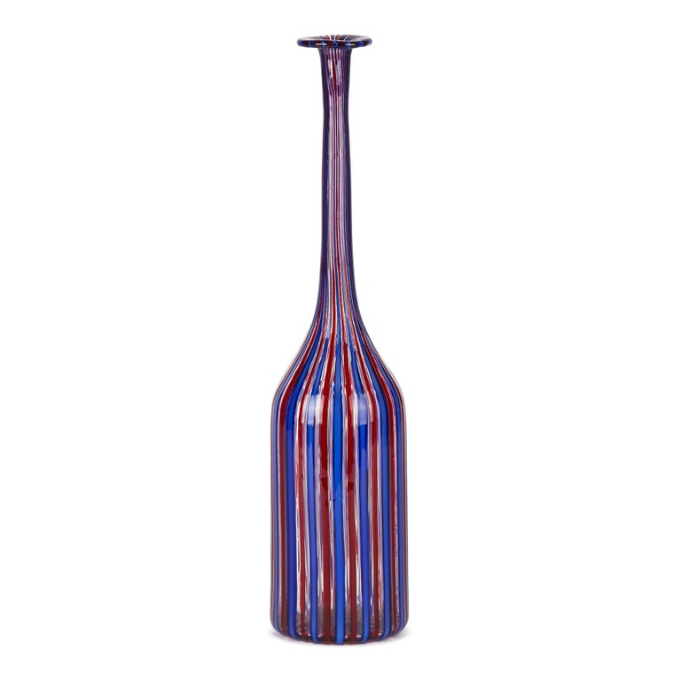 A stylish vintage Italian Murano art glass decanter or bottle vase with alternate red and blue ribboning set within clear glass by renowned glass makers Fratelli Toso. The elegant tall cylindrical shaped vase has a narrow neck with a fold back flat