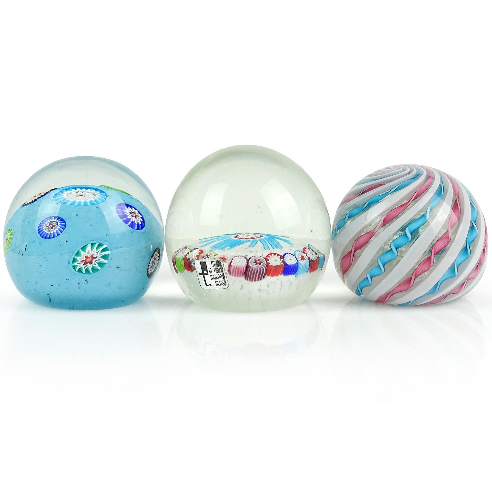 Priced per item (3 available as shown). Beautiful Murano hand blown Italian art glass paperweights. Documented to the Fratelli Toso company. The first is a blue ground with rainbow color millefiori pieces paperweight. Next, a white ground