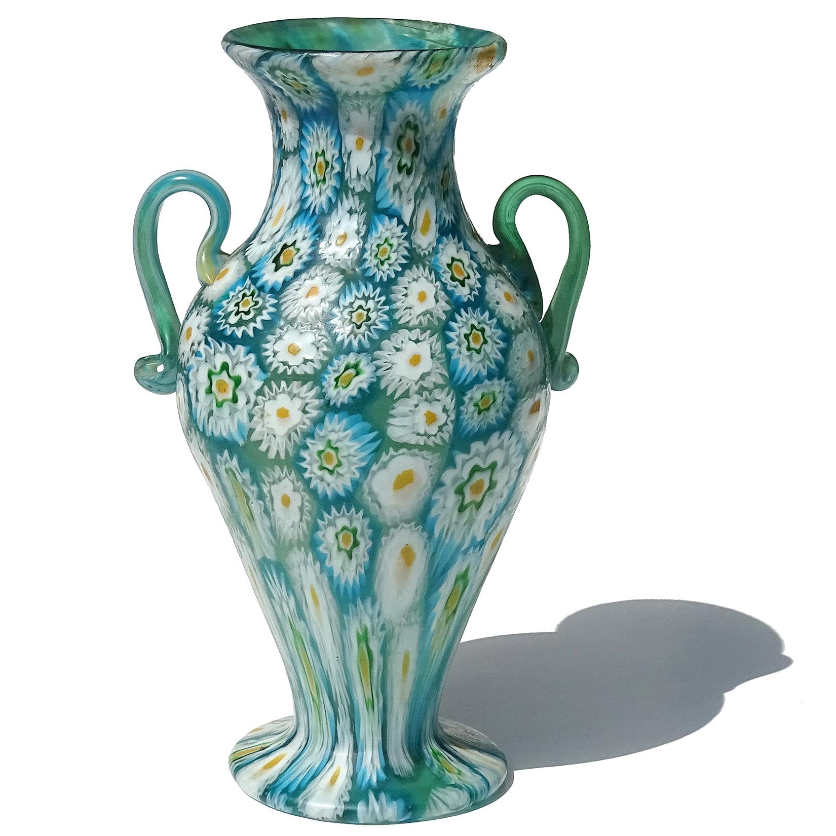 Beautiful antique Murano hand blown millefiori flower mosaic Italian art glass decorative double handles vase. Documented to the Fratelli Toso company, circa 1910-1930. Created in a classical shape with an alternating pattern of vertical rows in 2
