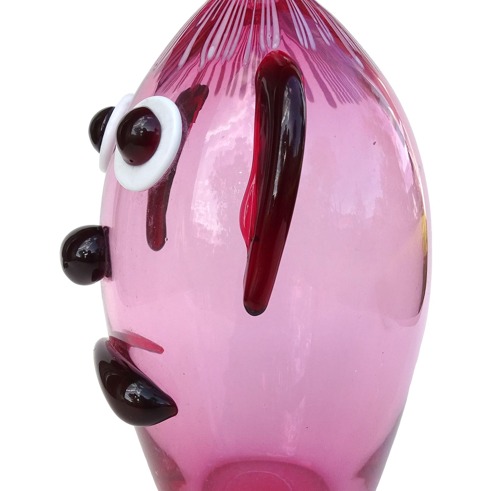 Cute and rare, vintage Murano hand blown Italian art glass clown face bottle / vase in pink, with red accents. Documented to the Fratelli Toso Company. The piece has applied ears, big eyes, a frown and threads of light pink glass for the hair. Would