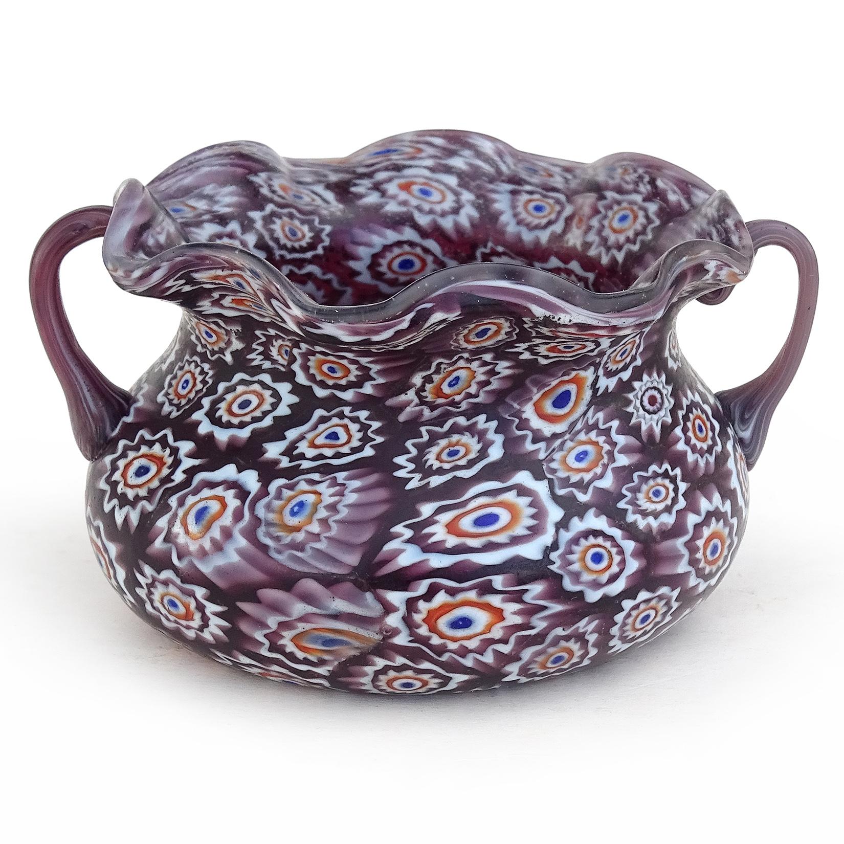 Beautiful antique Murano hand blown millefiori mosaic Italian art glass decorative bowl. Documented to the Fratelli Toso Company, circa 1900-1920. The bowl has a dark purple background color, with white, orange and blue flowers. It has a double