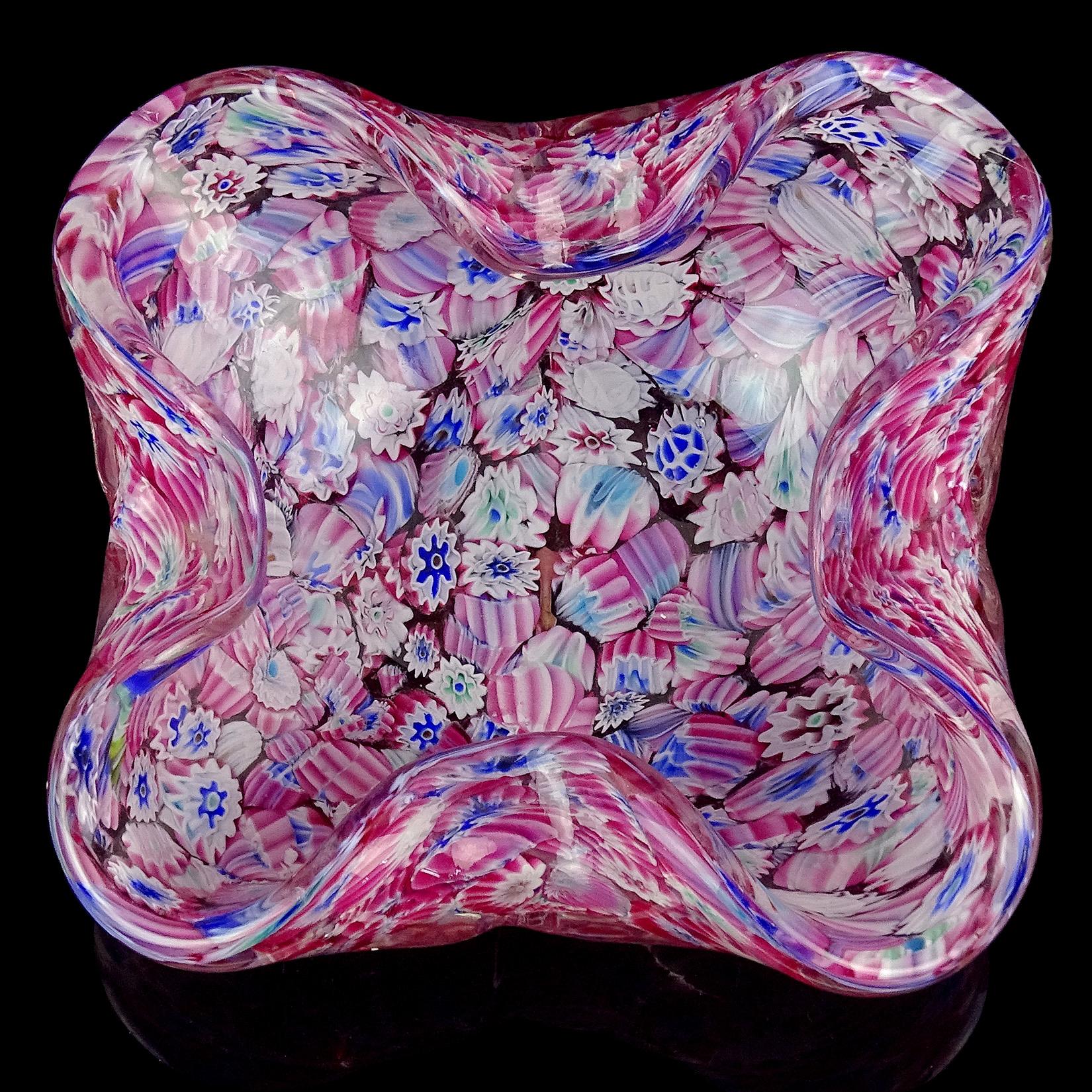 Beautiful vintage Murano hand blown magenta pink, with blue and white millefiori flowers Italian art glass decorative bowl. Attributed to the Fratelli Toso company. The piece has an irregular squared shape, with folds at the edges. The mosaic flower