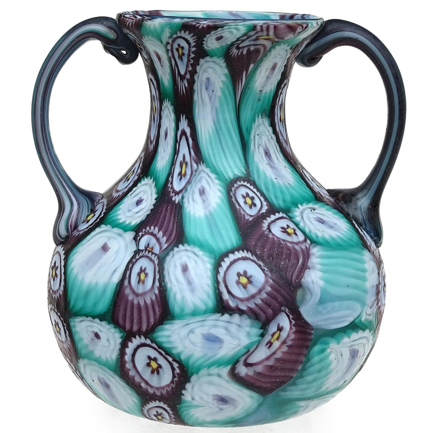 Beautiful antique Murano hand blown millefiori flower mosaic Italian art glass decorative double handles vase. Documented to the Fratelli Toso company, circa 1910-1930. It has a bulbous shape with vertical rows of light blue with white, and purple