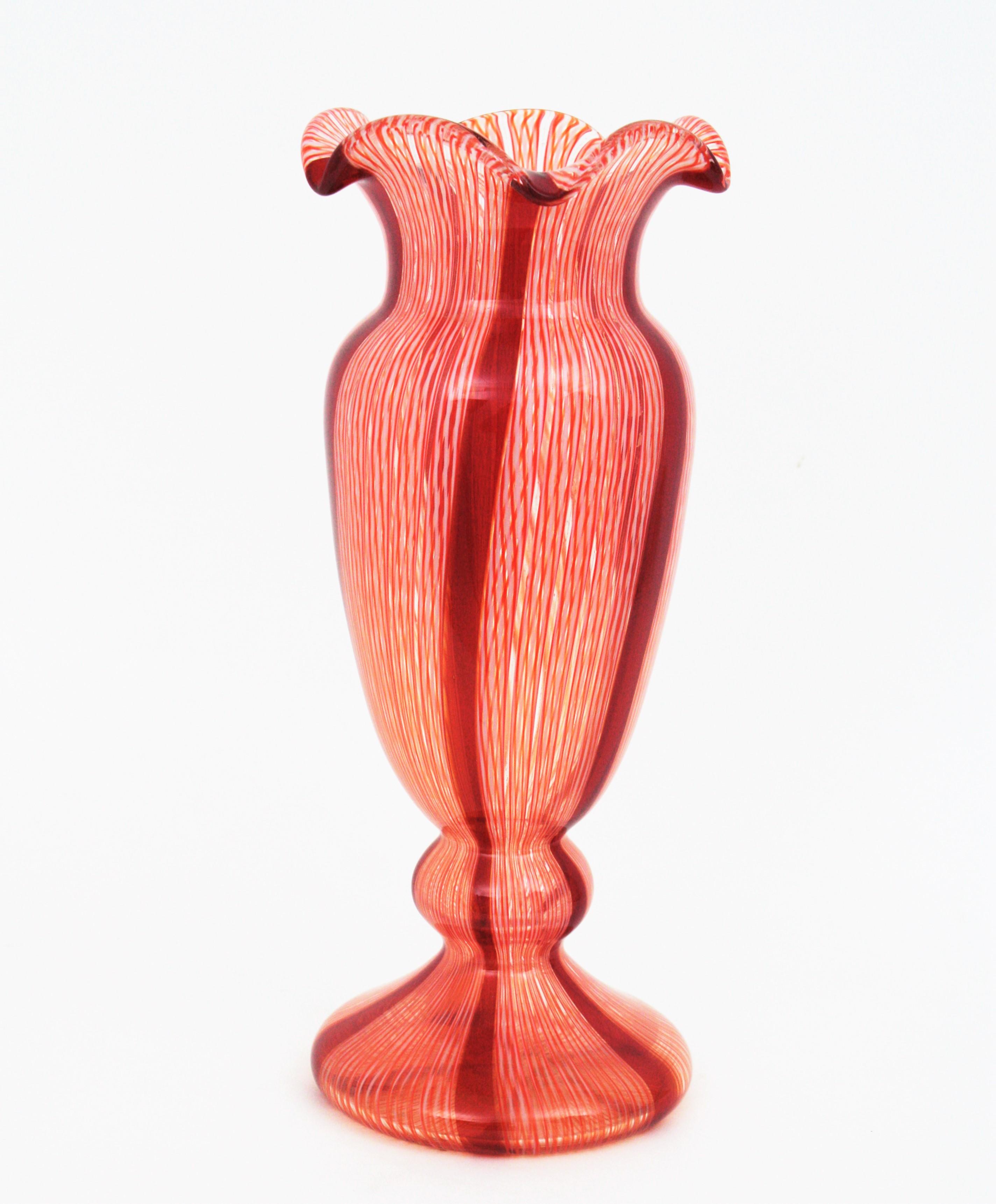 Skulpturale Vase aus geblasenem Zanfirico-Murano-Glas des frühen 20. Jahrhunderts mit roten und weißen Bändern.  Wird Fratelli Toso zugeschrieben. 
Hergestellt mit der Caneworking-Glasbläsertechnik in rubinrotem und weißem Glas mit gelben Akzenten.