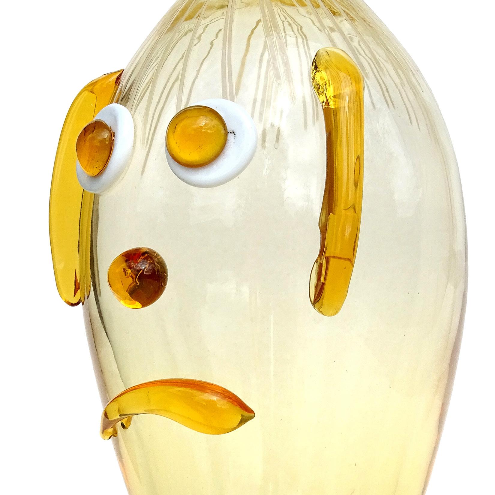 Cute and rare, vintage Murano hand blown yellow orange Italian art glass clown face decanter. Documented to the Fratelli Toso Company. The piece has applied ears, big eyes, a frown and threads of light pink glass for the hair. Would make a great
