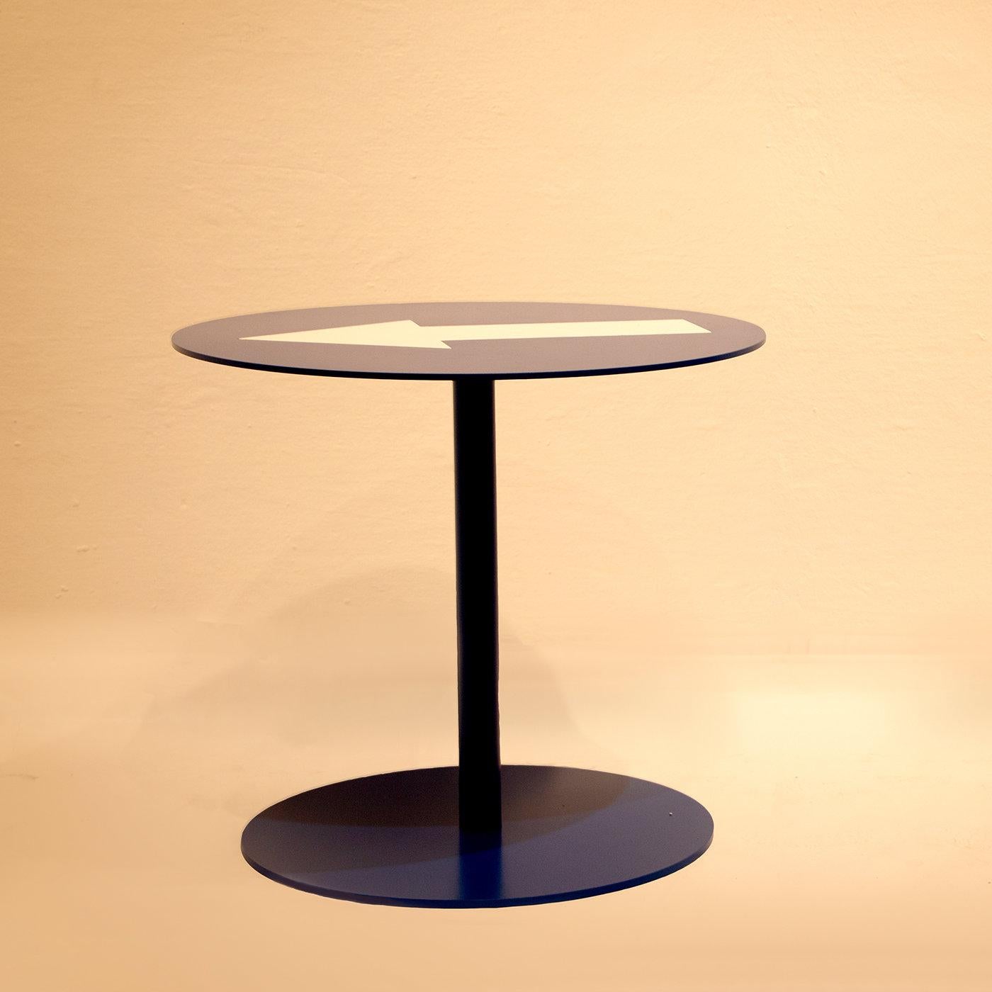 Handcrafted entirely of iron and finished in dark blue, this coffee table is part of a series that turns road signs into original and fun furniture pieces for contemporary home and office decors. The round top showcasing a white arrow is supported