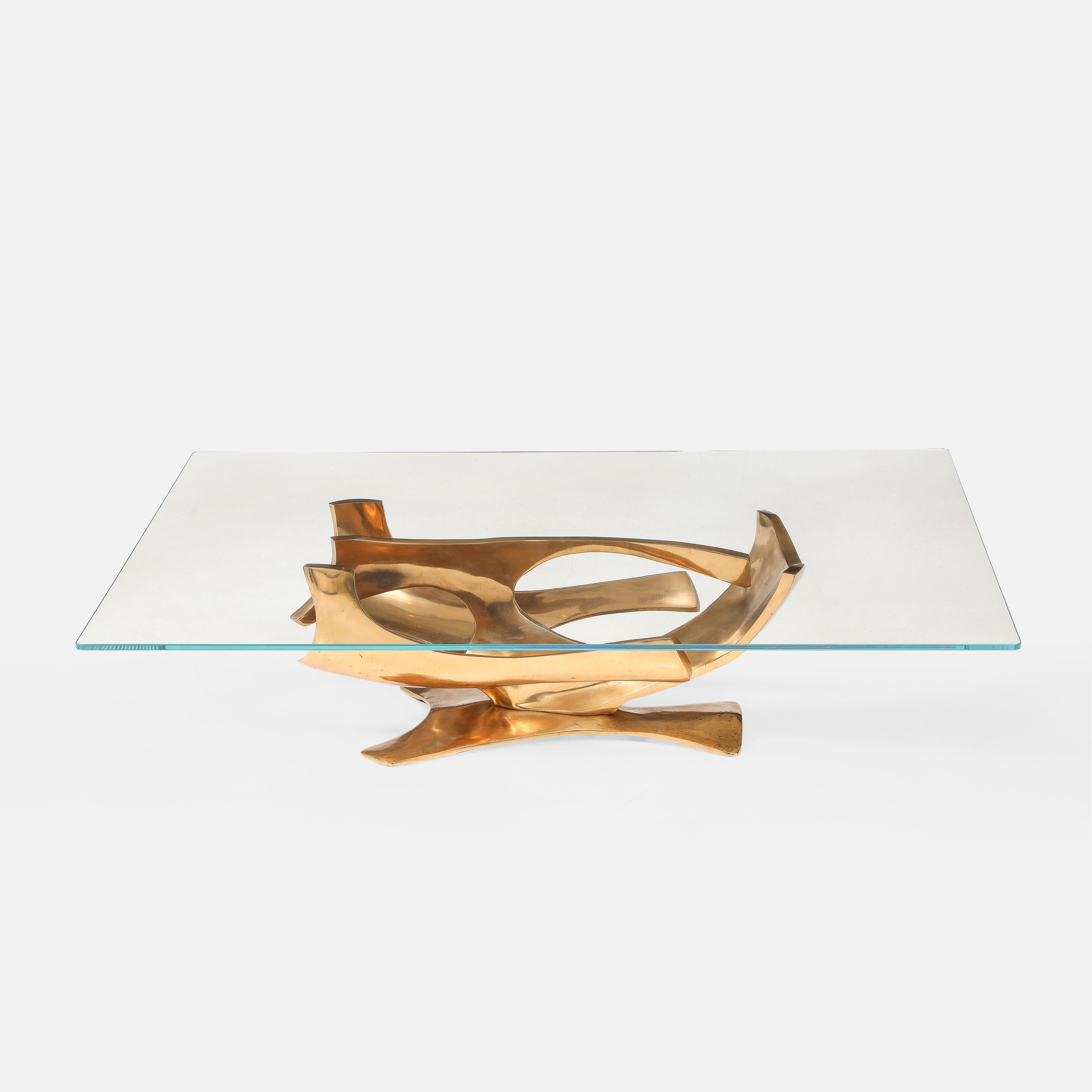 Fred Brouard rare coffee table with abstract sculptural gilt bronze base and rectangular plate glass top, France, 1970s. This exquisite coffee table has a dynamic and organic curved gilt bronze base resembling a stylized bird in flight. The