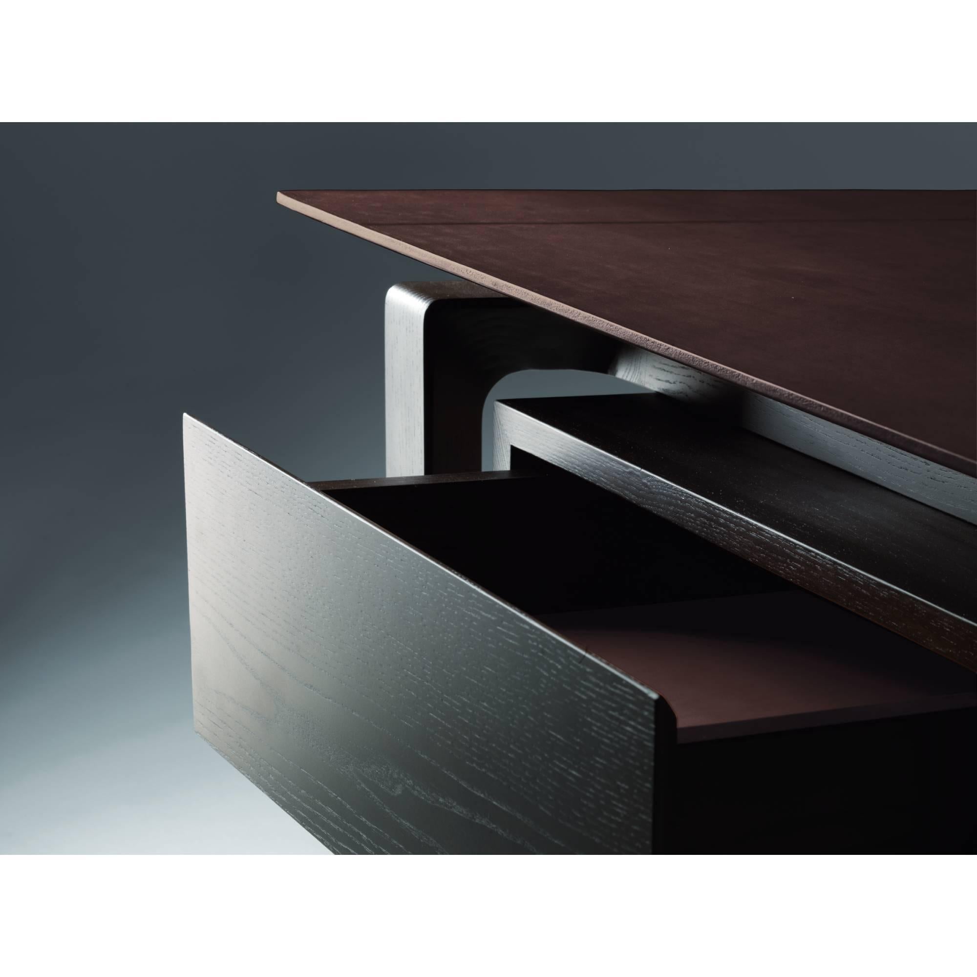Dieser Schreibtisch ist eine Begegnung mit leichten, fast ätherischen Geometrien. Roberto Lazzeroni entwirft ein Möbelstück, bei dem das visuelle Vergnügen einer durchgehenden Sattellederoberfläche durch zarte handgefertigte Einschnitte und kalte