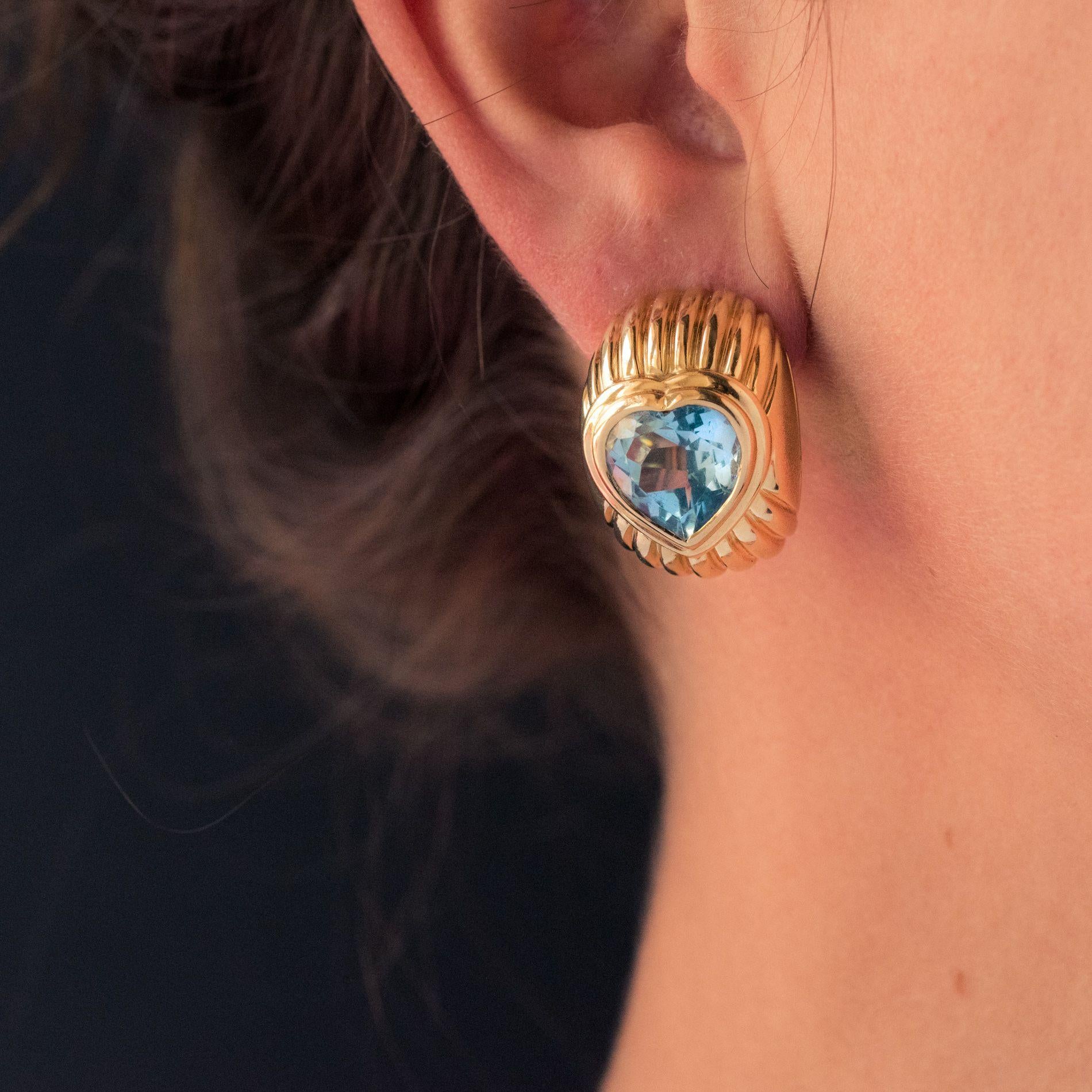Earrings in 18 karat yellow gold, eagle head hallmark.
This splendid pair of gold earrings is formed of a curved and gadrooned pattern set in the center of a splendid and luminous topaz cut in heart. The fastening system is a stud with safety