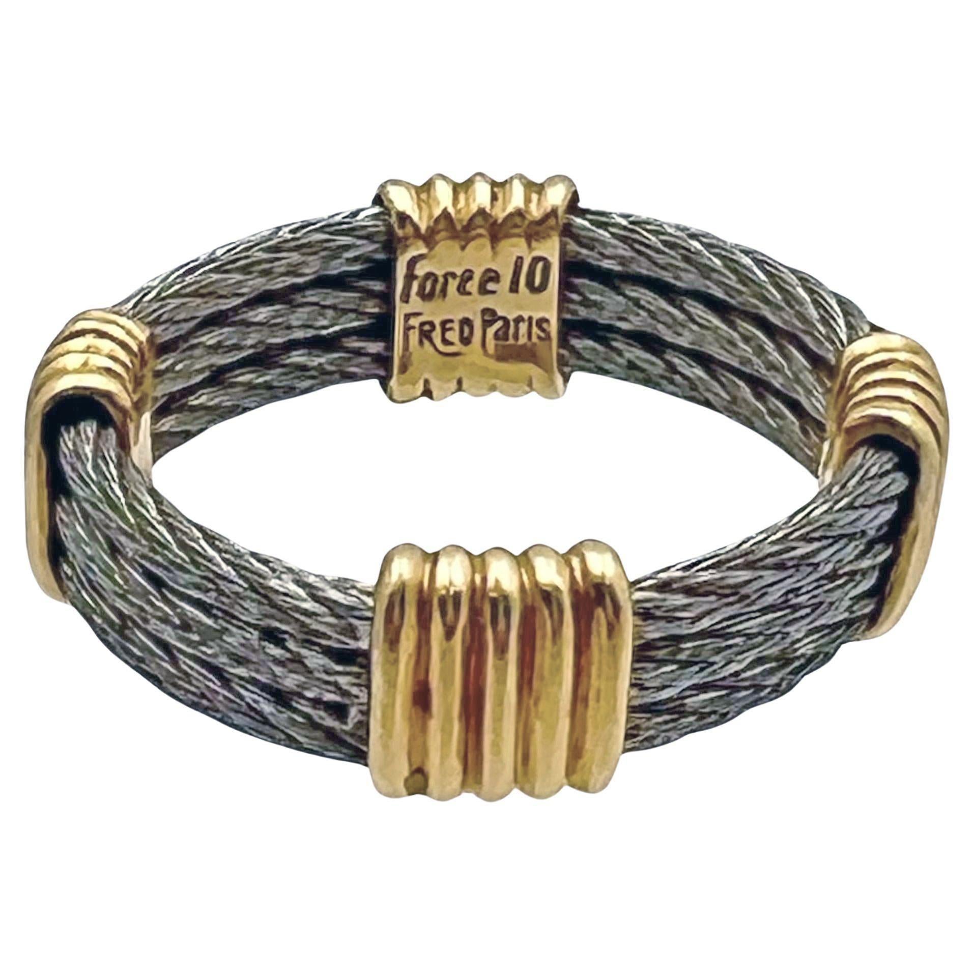Fred Paris 'Force 10' band ring in 18k yellow gold and stainless steel cable. Three rows of steel cable with four 18 karat yellow gold wraps.  Measuring width of 5.4mm (cables) and approximately 7.3mm (gold wraps).and Signed 'Force 10 Fred Paris'
