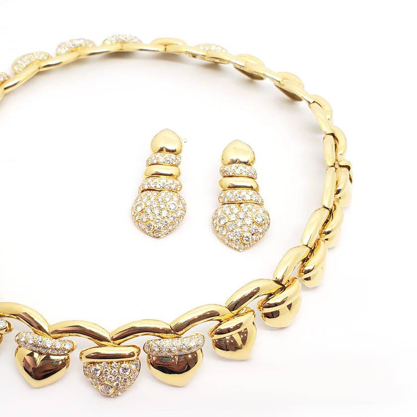 Signed Fred of Paris, this retro yellow gold, diamond necklace and earring set is a classic. The set is beautifully made in 18 karat yellow gold and features a matching choker necklace and dangle earrings. The necklace and earrings are in excellent