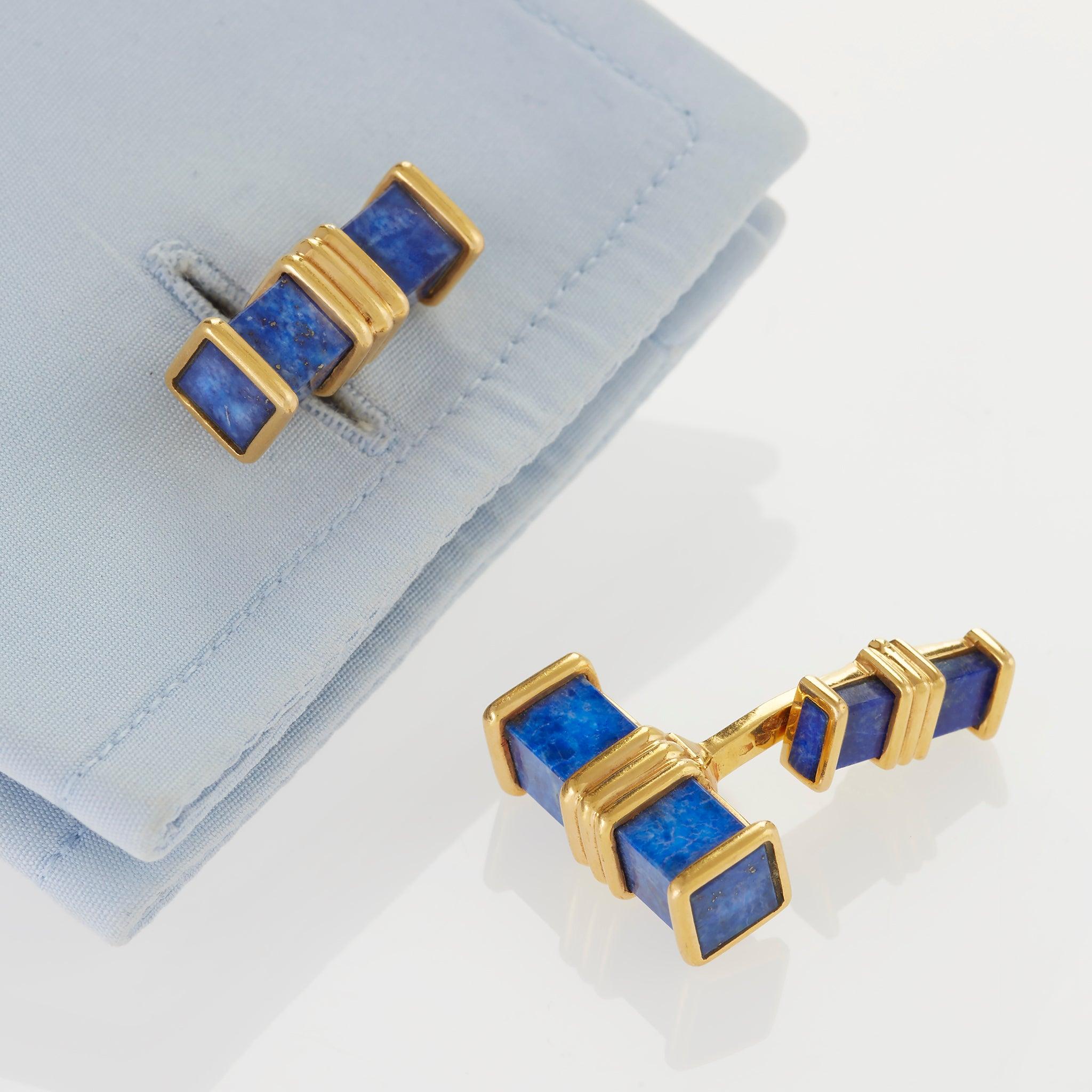 Created in the late 20th century by Fred, Paris, these cuff links are composed of lapis lazuli and 18K gold. Each double link is designed as a rectangular baton bound by a ridged mount, and joined by a gently curved bar to a smaller conforming lapis