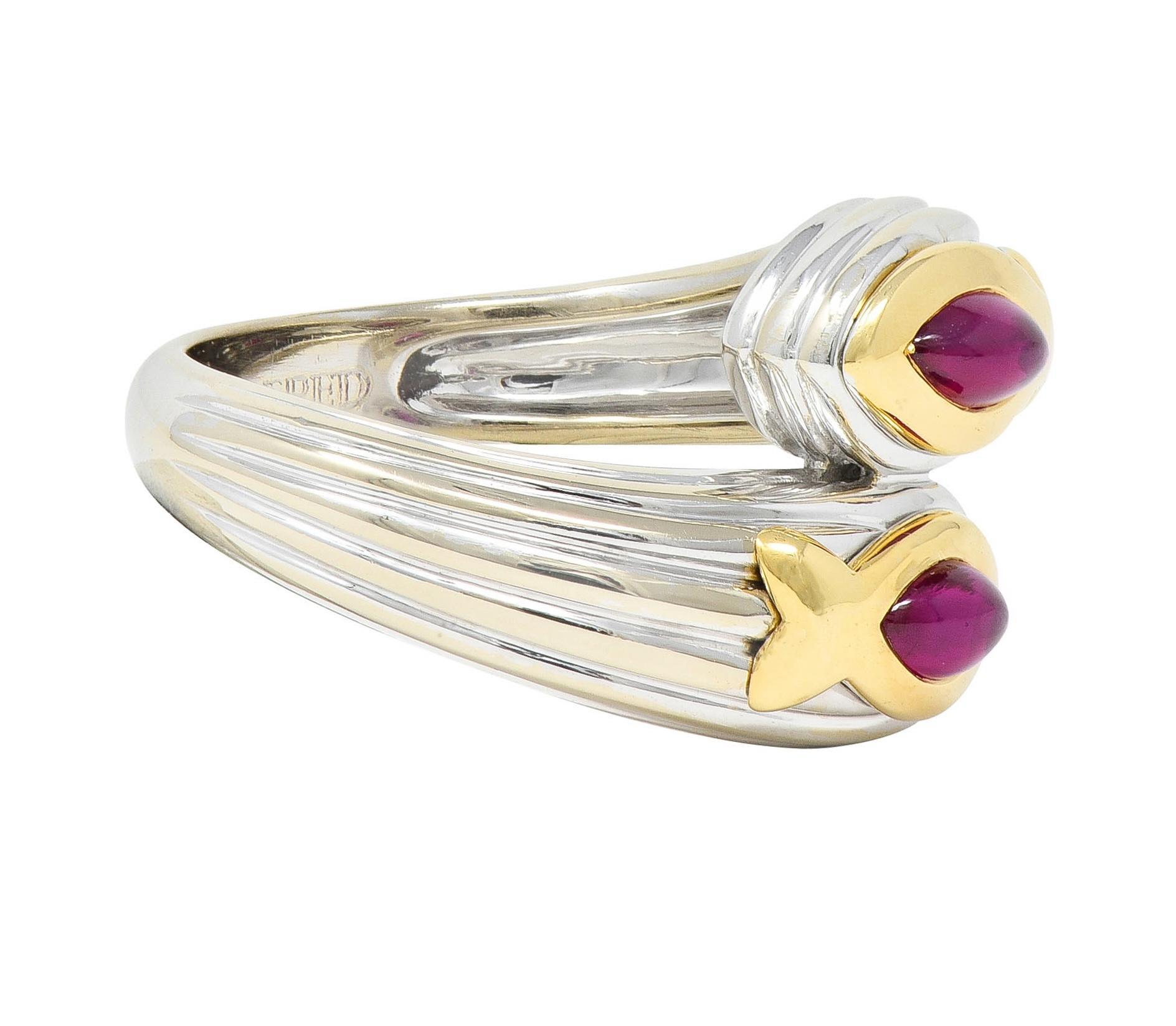 Designed as a white gold bypass ring with slightly domed terminals 
With ridged detail and featuring marquise-shaped ruby cabochons
Weighing approximately 0.60 carat total - transparent medium red
Flush set with yellow gold fish motif