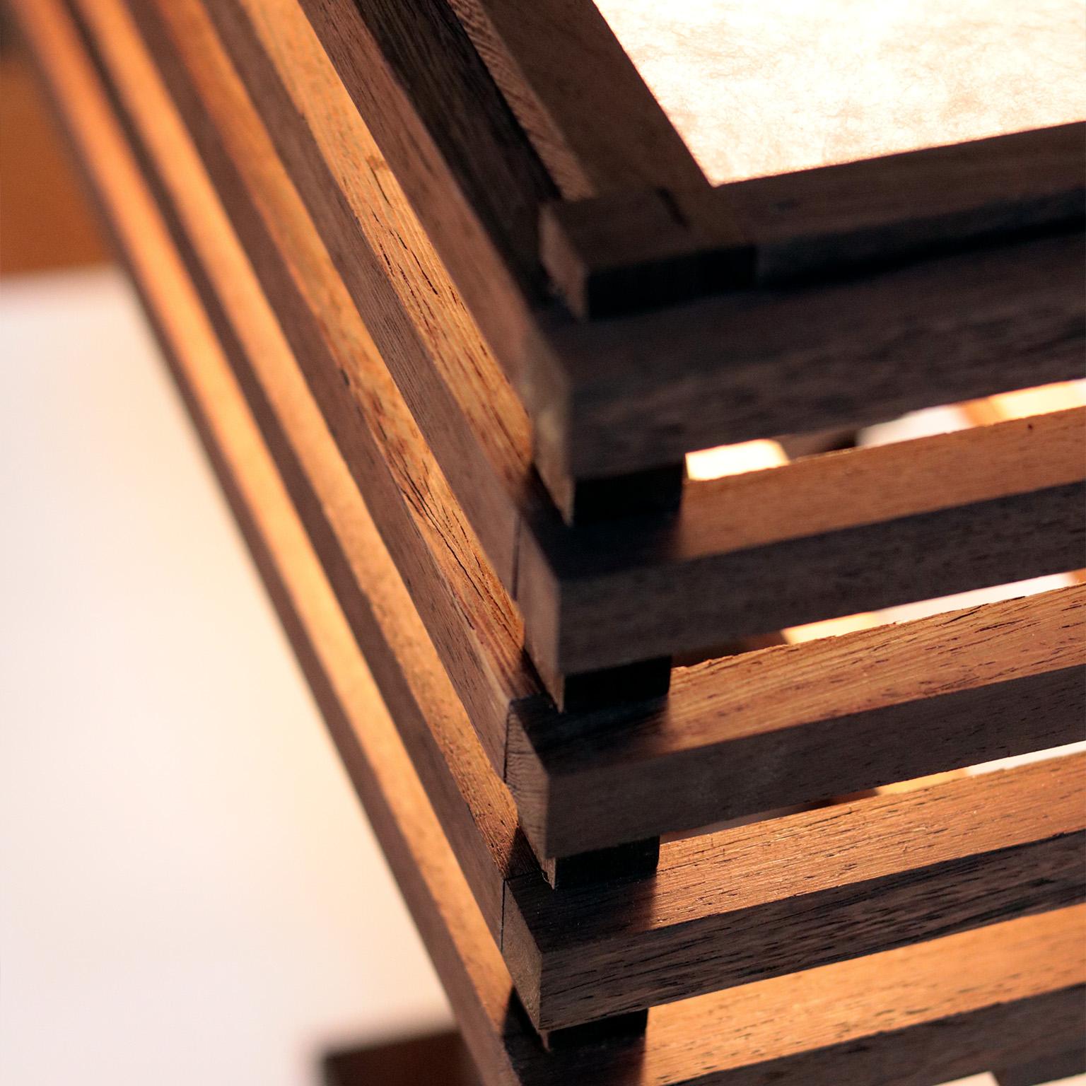La lampe de table Frederick est une pièce entièrement fabriquée à la main, à partir de bois de cale et de papier japonais.  La composition joue avec la linéarité et le mouvement organique.  Une lumière très intéressante qui ne manquera pas d'être