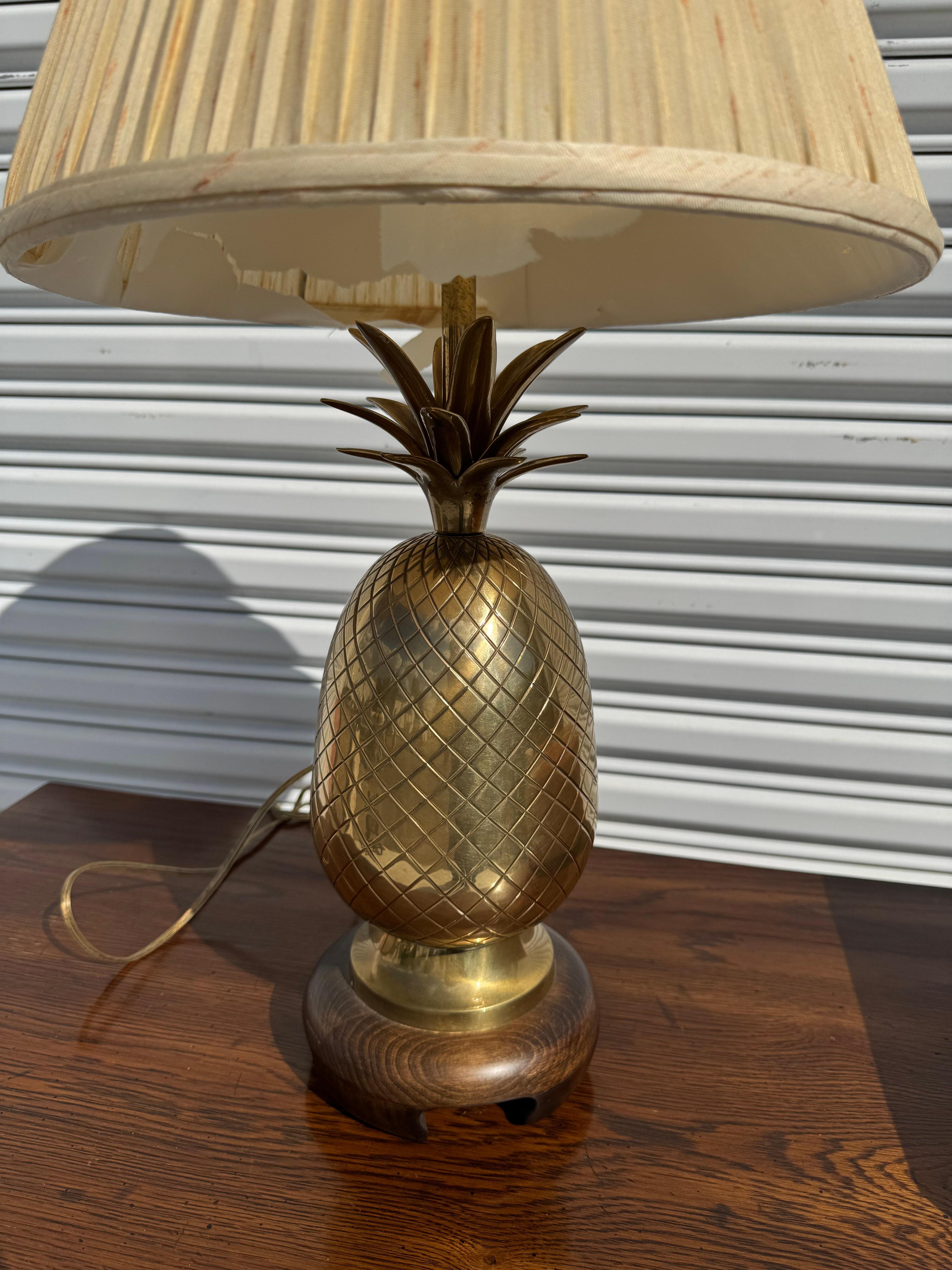 Questa è una lampada da tavolo a forma di ananas in ottone di Frederick Cooper. La Frederick Cooper lamp Co. ha sede a Chicago, Ill.
La lampada poggia su una base in legno massiccio. 
Il terminale è in ottone massiccio e il paralume è marchiato