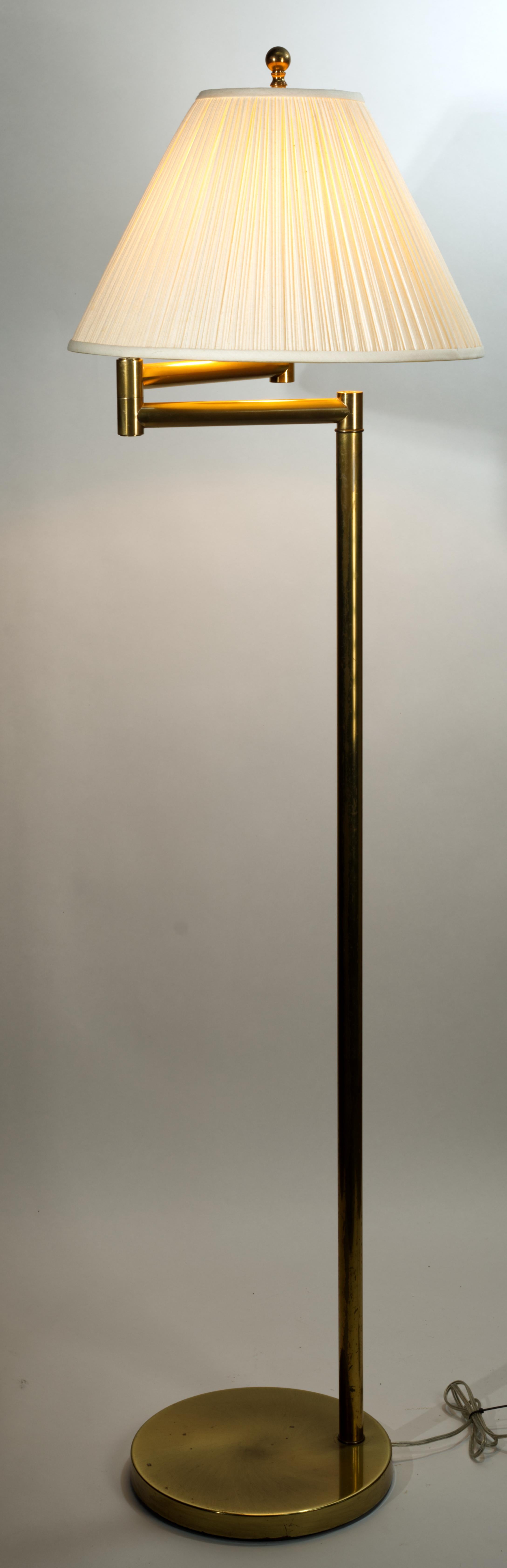 Vintage brass floor lamp features an adjustable swing arm design and heavy, weighted round base. It is fitted with the original socket, harp, and large decorative brass finial.

The lamp is marked on the underside of the base with the manufacturer's