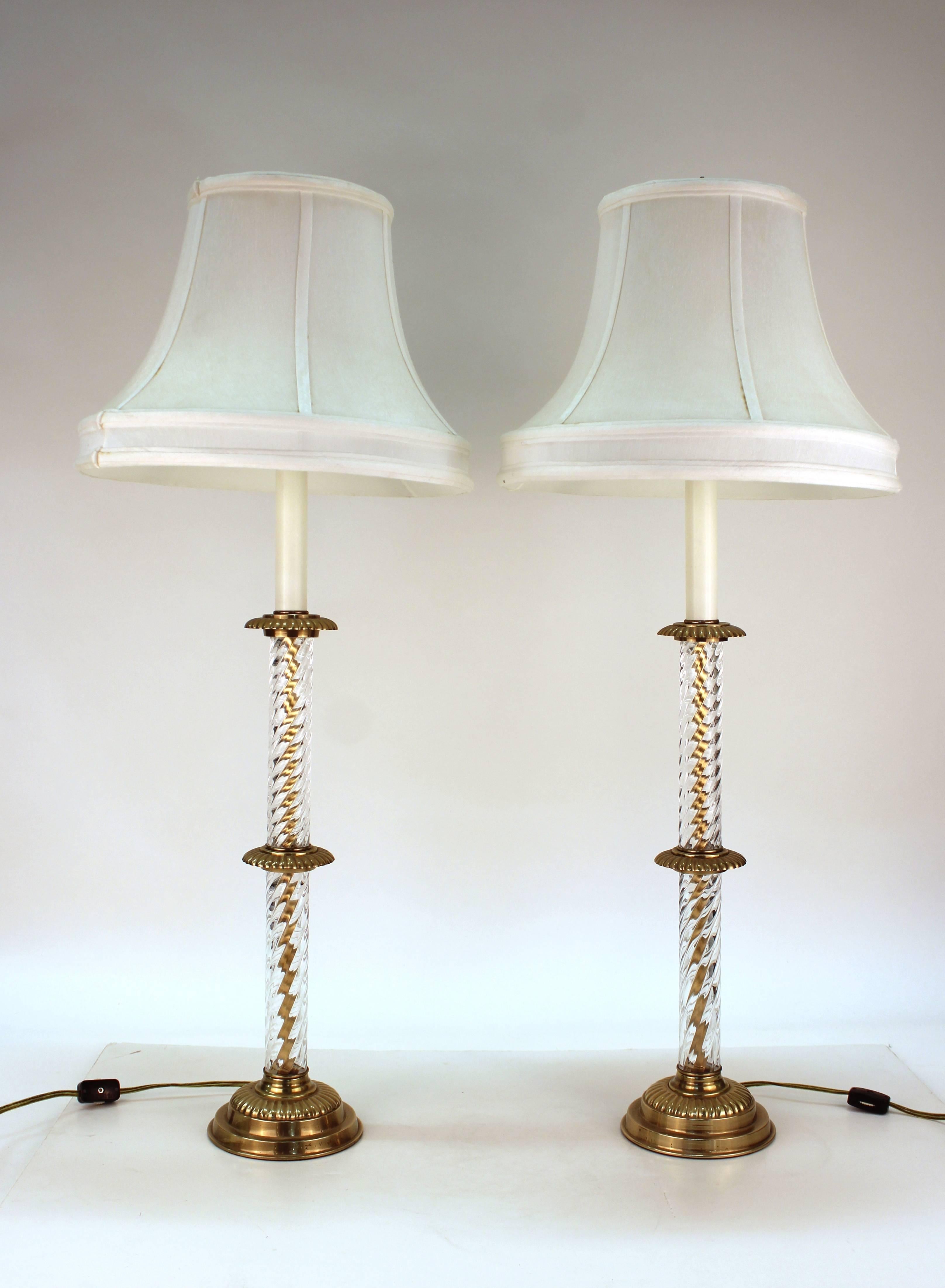 Frederick Cooper lamps with column motif dating from the 1970s. Crafted in cut crystal with twisting rope motif and intersecting brass plates. The pair also feature bevelled brass basses and white shades. Minor wear to the brass on the bases but in