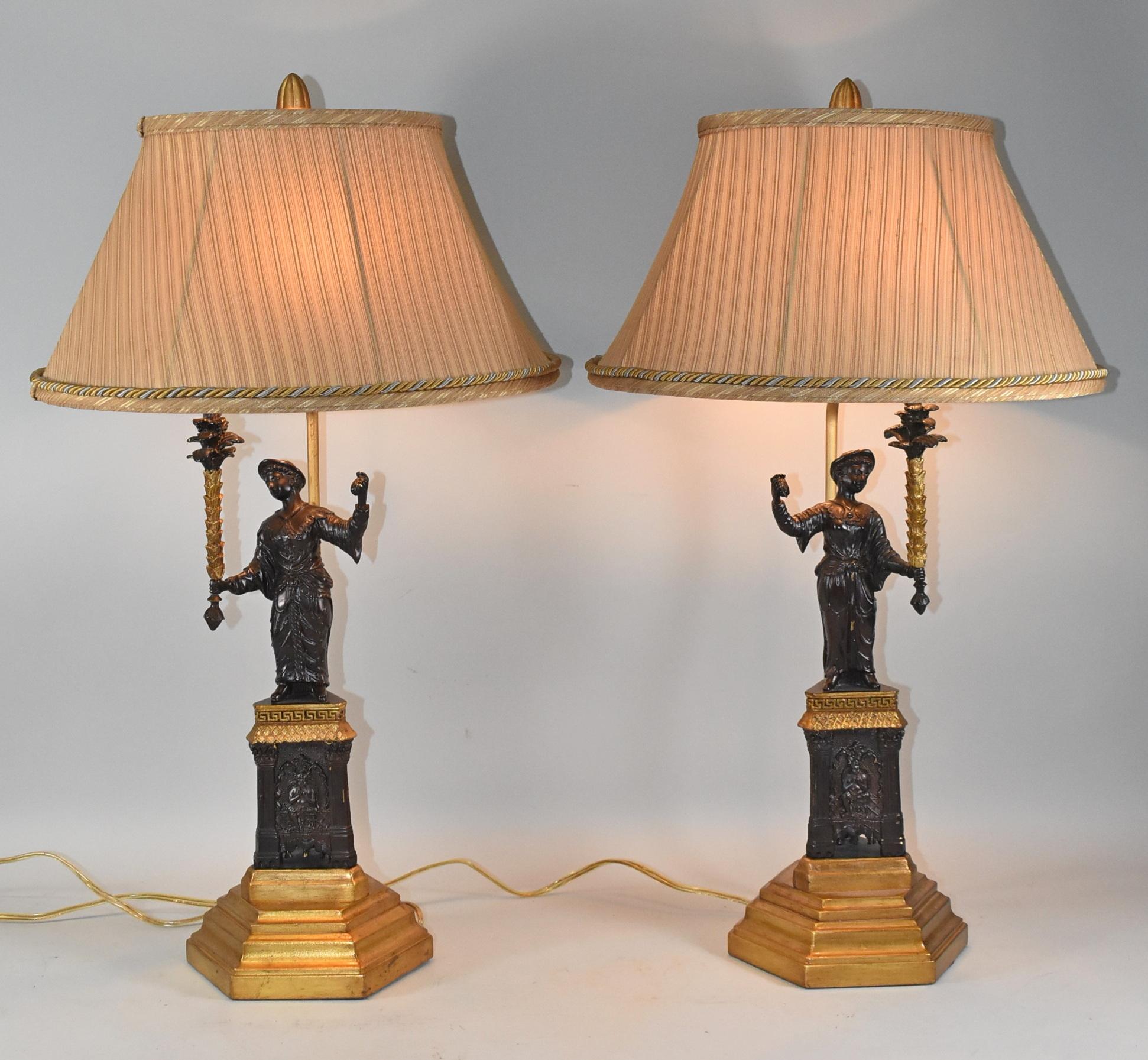 Paire de lampes Frederick Cooper de style Empire présentant une étonnante sculpture féminine en bronze sur une base sculptée. Comprend les abat-jour en soie d'origine avec bordure en cordon. La lampe mesure 28