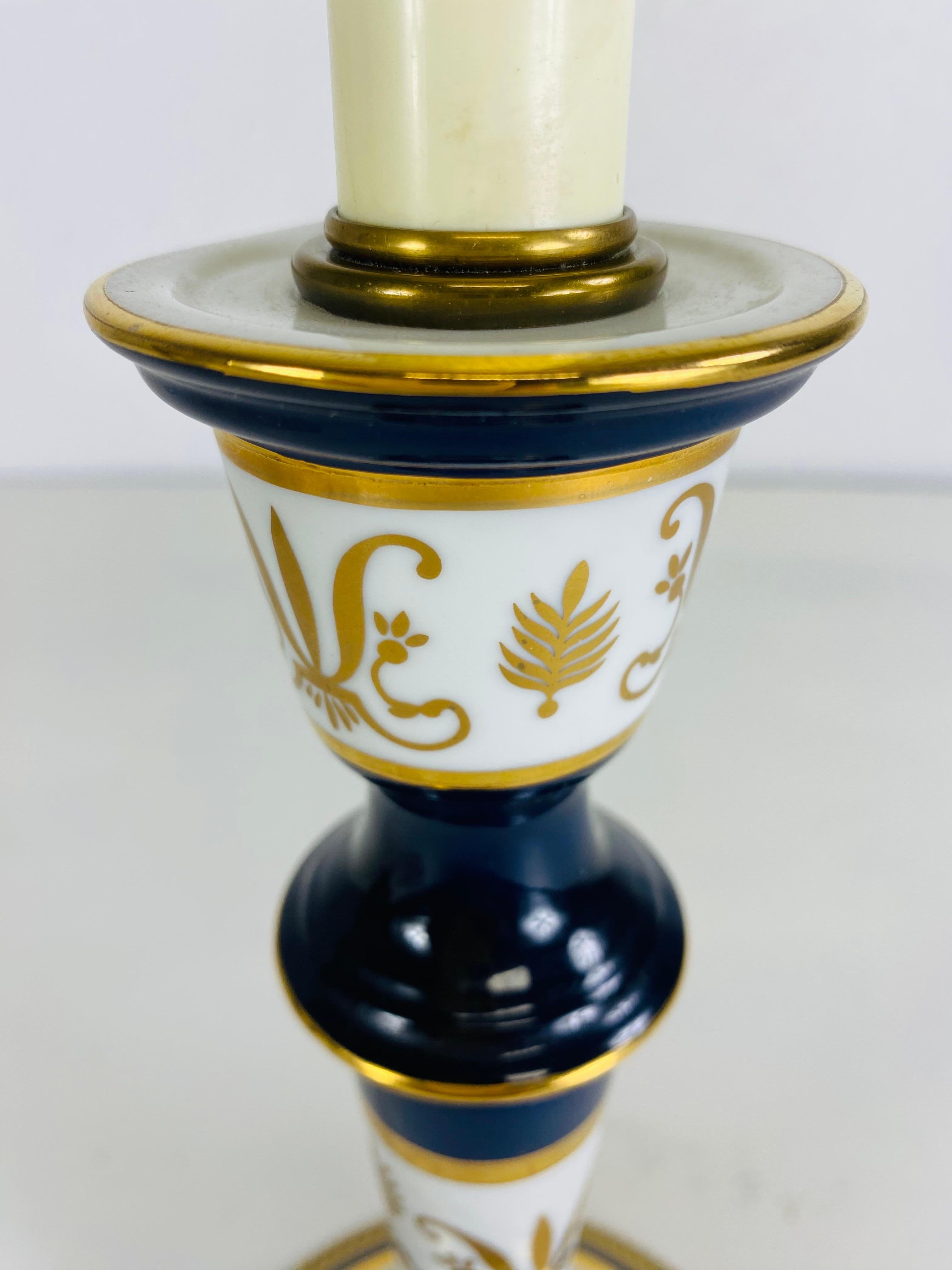 Se trata de una lámpara de mesa vintage de porcelana pintada a mano de Frederick Cooper. Esta lámpara Frederick Cooper está pintada a mano en estilo Imperio con tonos azul cobalto oscuro, dorado y verde. La lámpara se apoya en una base de latón