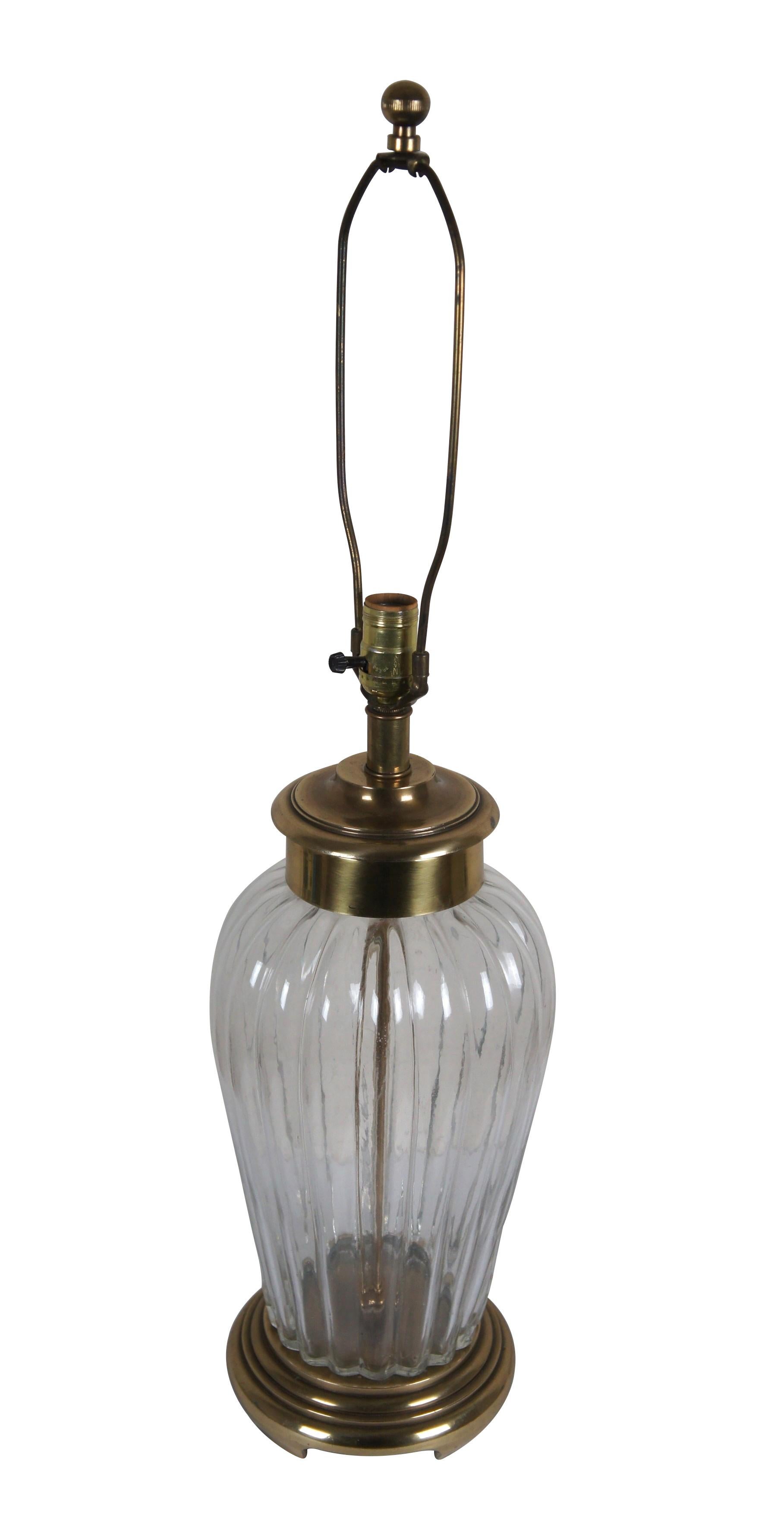 Lámpara de sobremesa de Frederick Cooper de finales del siglo XX. Jarra de jengibre / forma de urna con base y tapón / tapa de latón y cuerpo de cristal transparente estriado. Incluye arpa y remate orbital de latón estriado.

Dimensiones:
9