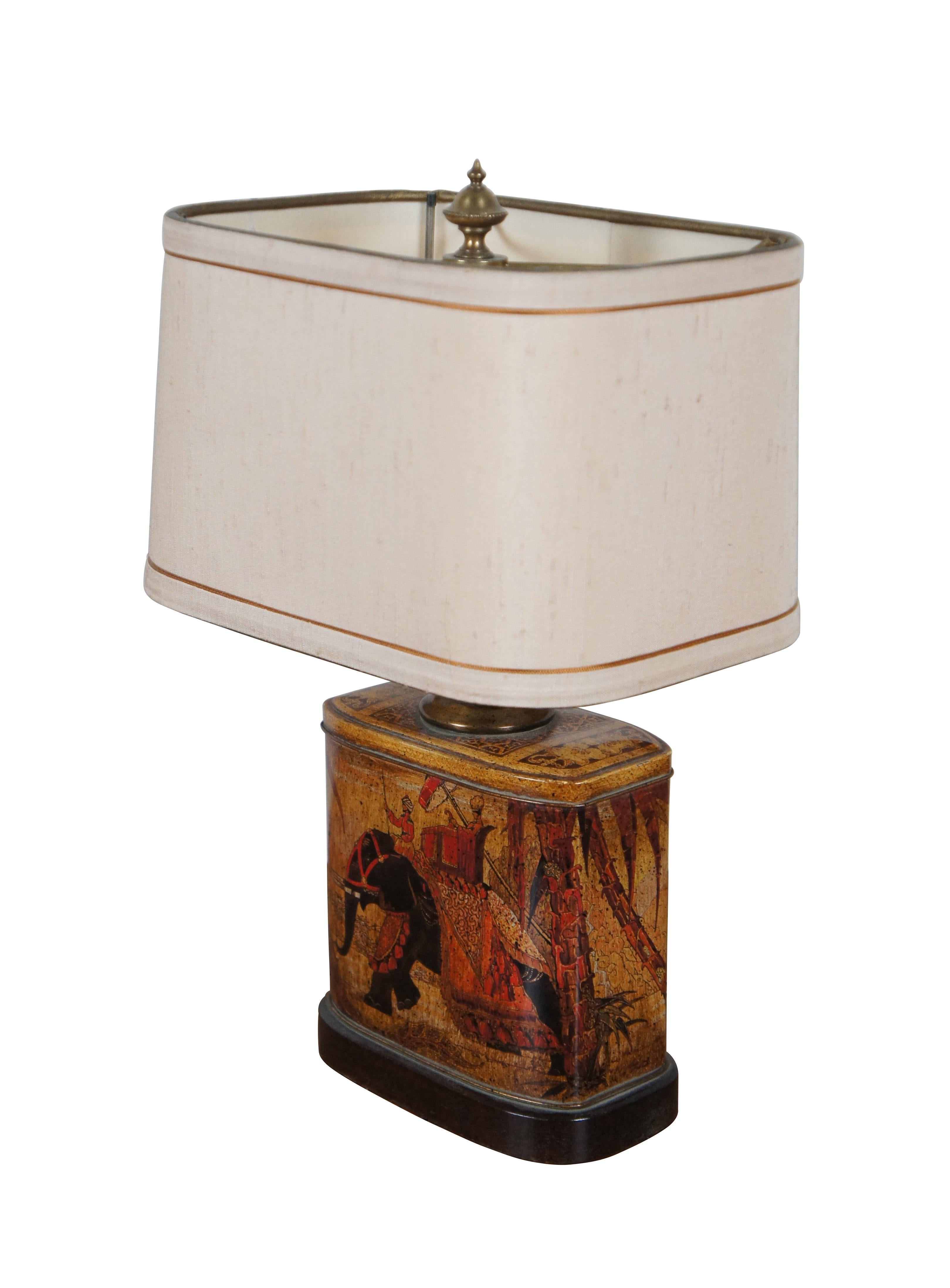 Late 20th century Frederick Cooper Wildwood table lamp featuring a wooden base, rectangular tin tea caddy painted with a British Colonial scene of figures riding a howdah on an Indian elephant, and a fixed L shaped harp. Includes gold trimmed, white