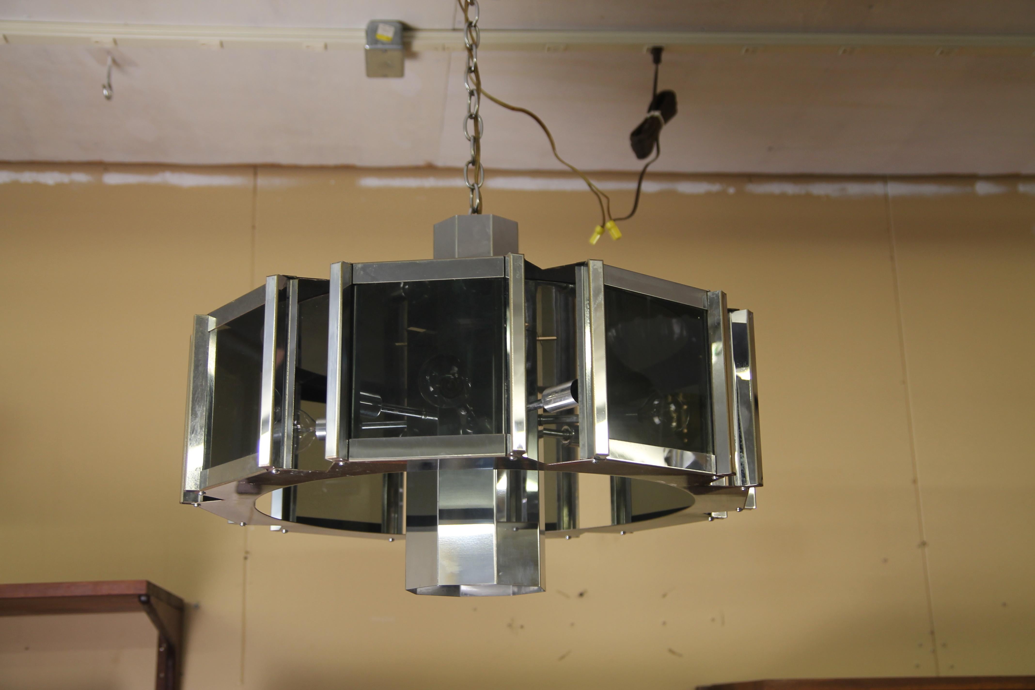 Great 1970s chrome chandelier by Frederick Raymond. Has one center light with 8 smaller lights that shine through the 8 glass panels. The center light can be switched off.