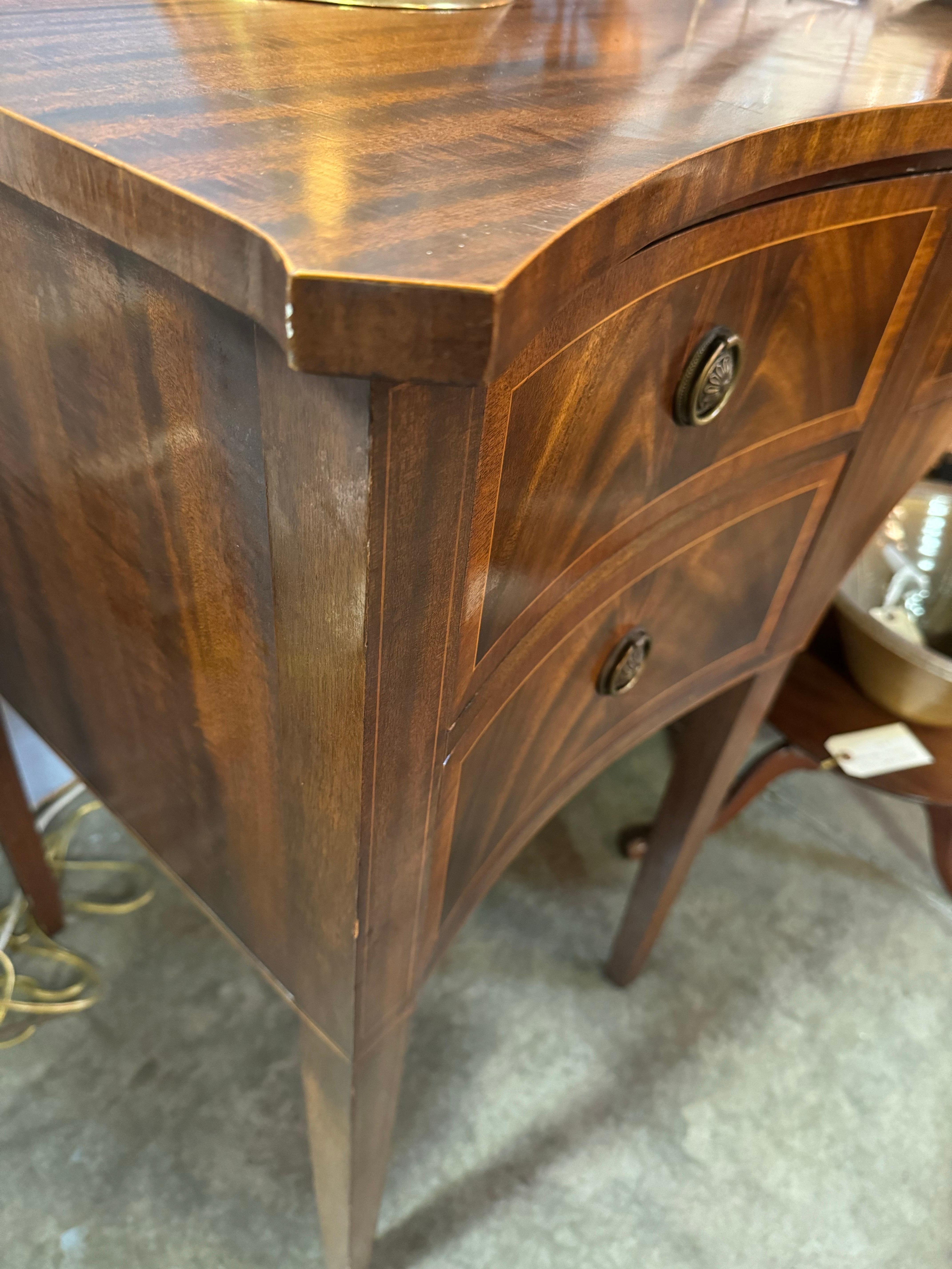 Un'antica credenza in mogano di Frederick Tibbenham di Ipswich, Inghilterra. 

Il piano conformato a fasce incrociate sormonta cinque cassetti con fregio a coda di rondine, impiallacciatura in mogano bombato, fasce in legno satinato e tiretti ad