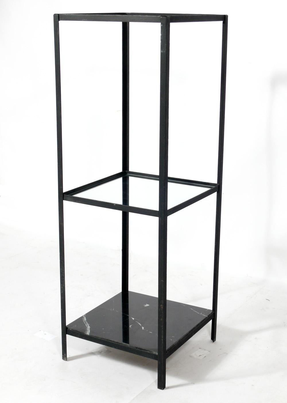 Clean lined iron, marble, and glass vitrine or bookshelf, designed by Frederick Weinberg, American, circa 1950s. It features a black marble piece at the bottom with two glass shelves above it. It is a versatile size and can be used for displaying