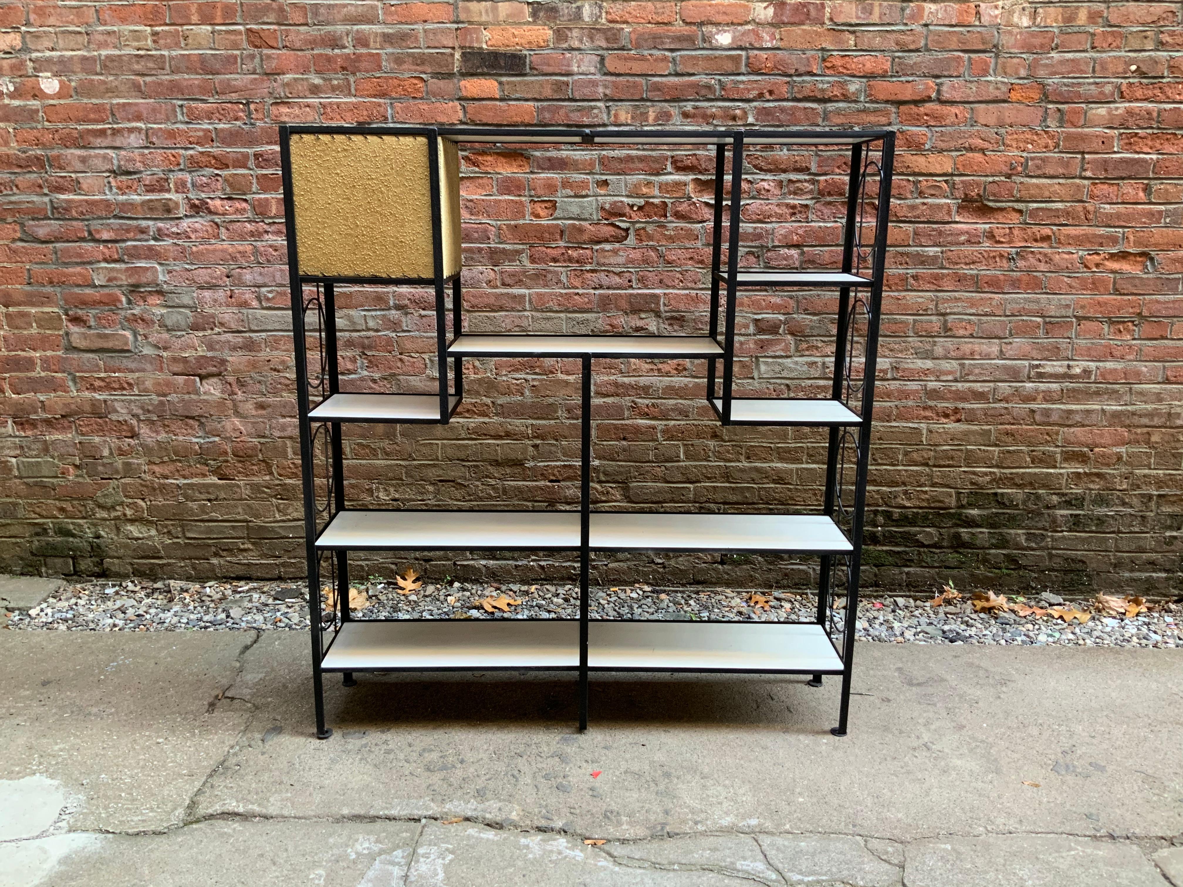Frederick Weinberg iron shelving unit with built in lamp. Iron frame with original white Masonite shelves. The unit features a built in lamp with original vellum shade. Re-wired. Some scratches, staining and losses to shelves. Good overall