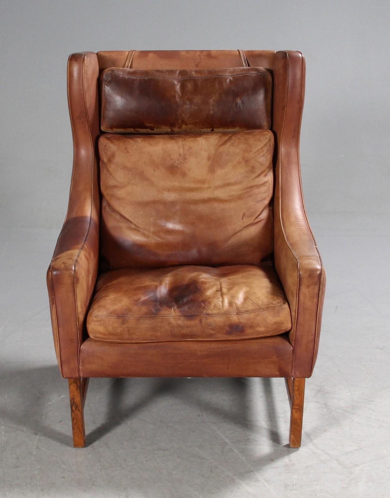 Cognac leather wingback chairs, designed by Fredrik Kayser for Vatne Møbler, Norway, circa 1964. Hardwood legs, and adjustable headrests with weighted straps. 
Used condition.

