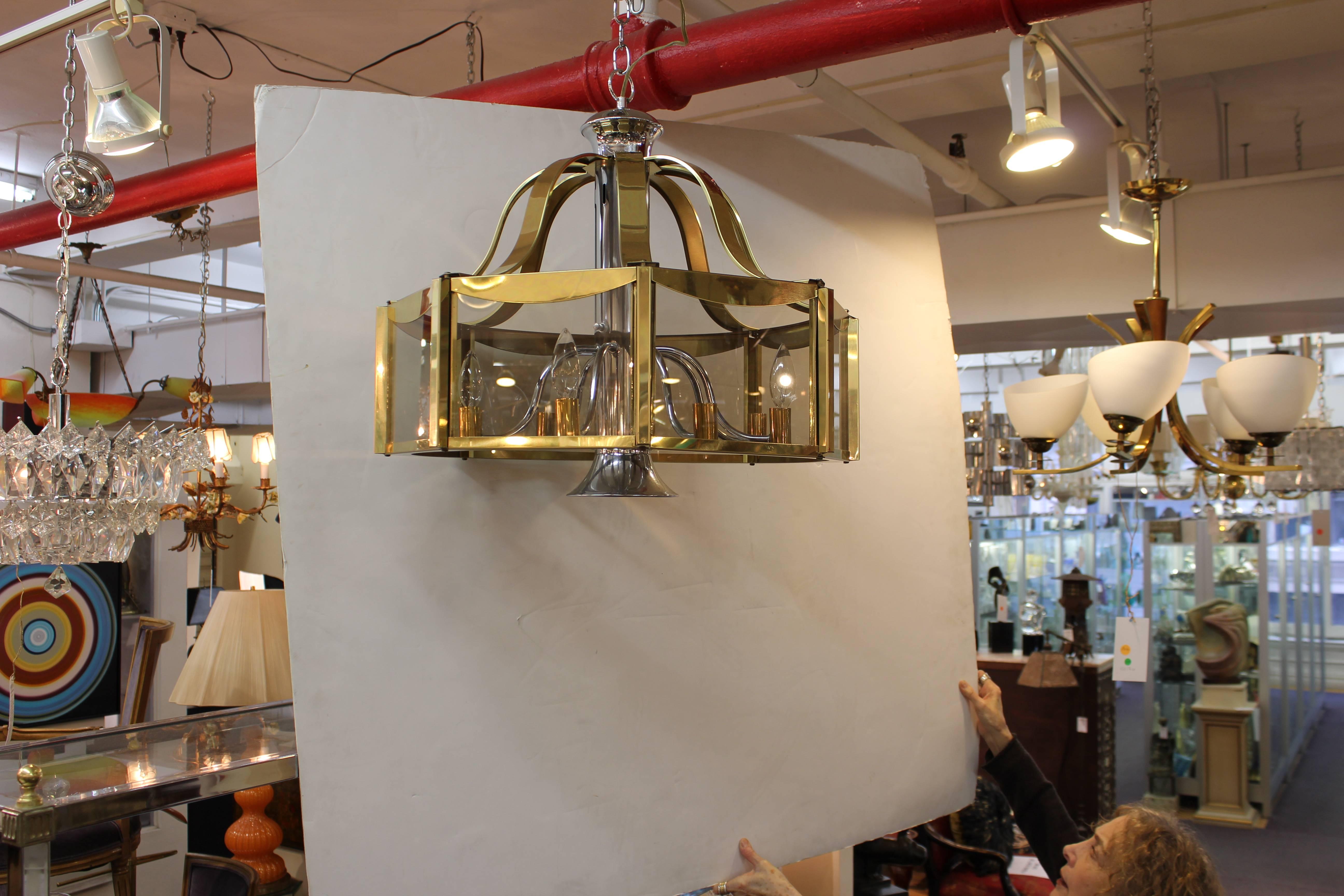 Fredrick Ramond chandelier dating from the 1970s. The piece features eight glass panels in a brass frame suspended from curved brass panels. The central pillar is crafted in chrome with eight brass tipped arms. Recently re-wired to accepts