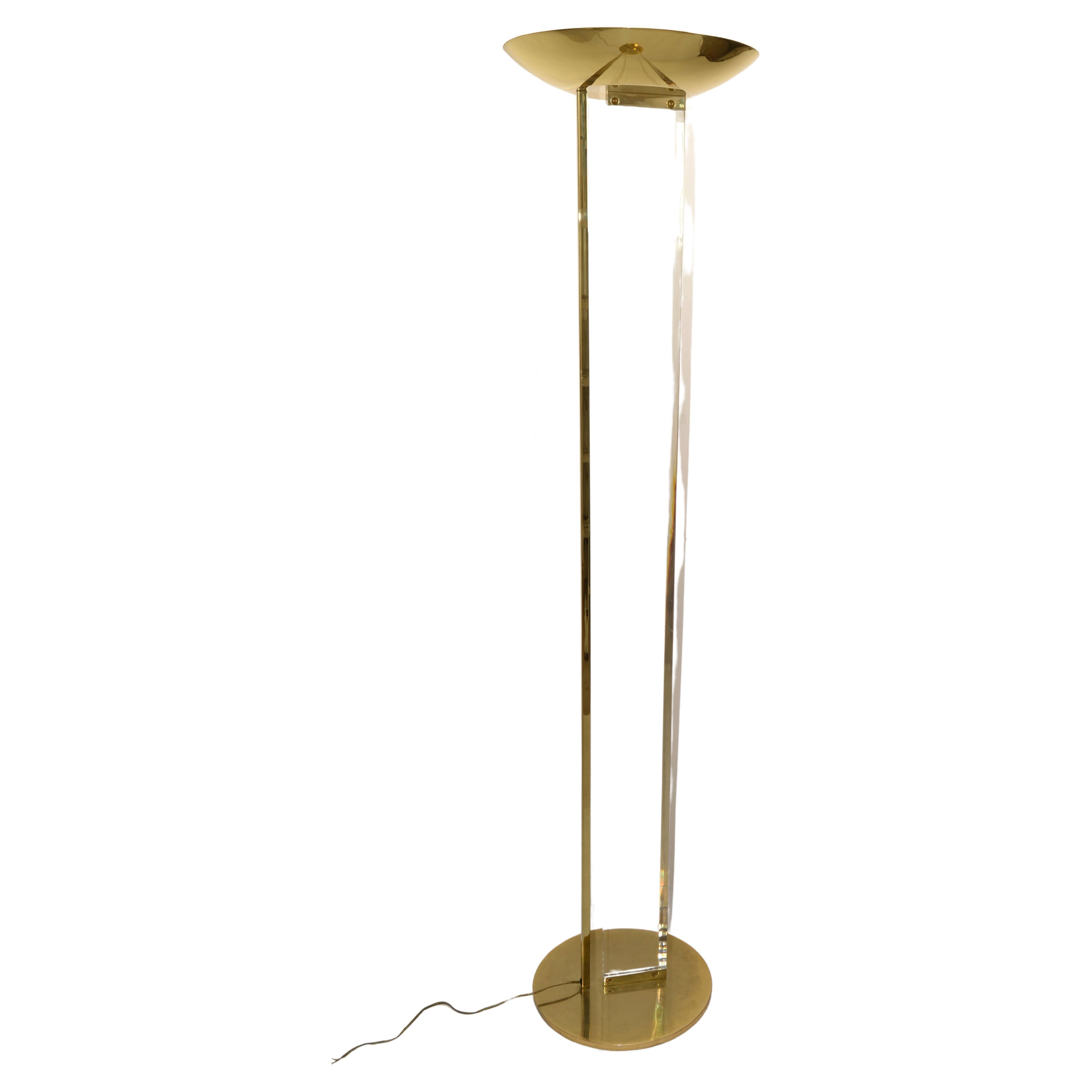 This elegant and classy floor lamp is made of brass and clear Lucite. The uplighter shade, foot and side of the pole are made of brass whereas the pole itself made of Lucite. 
Lovely detail is the angled cut in the Lucite all along the stem.
This