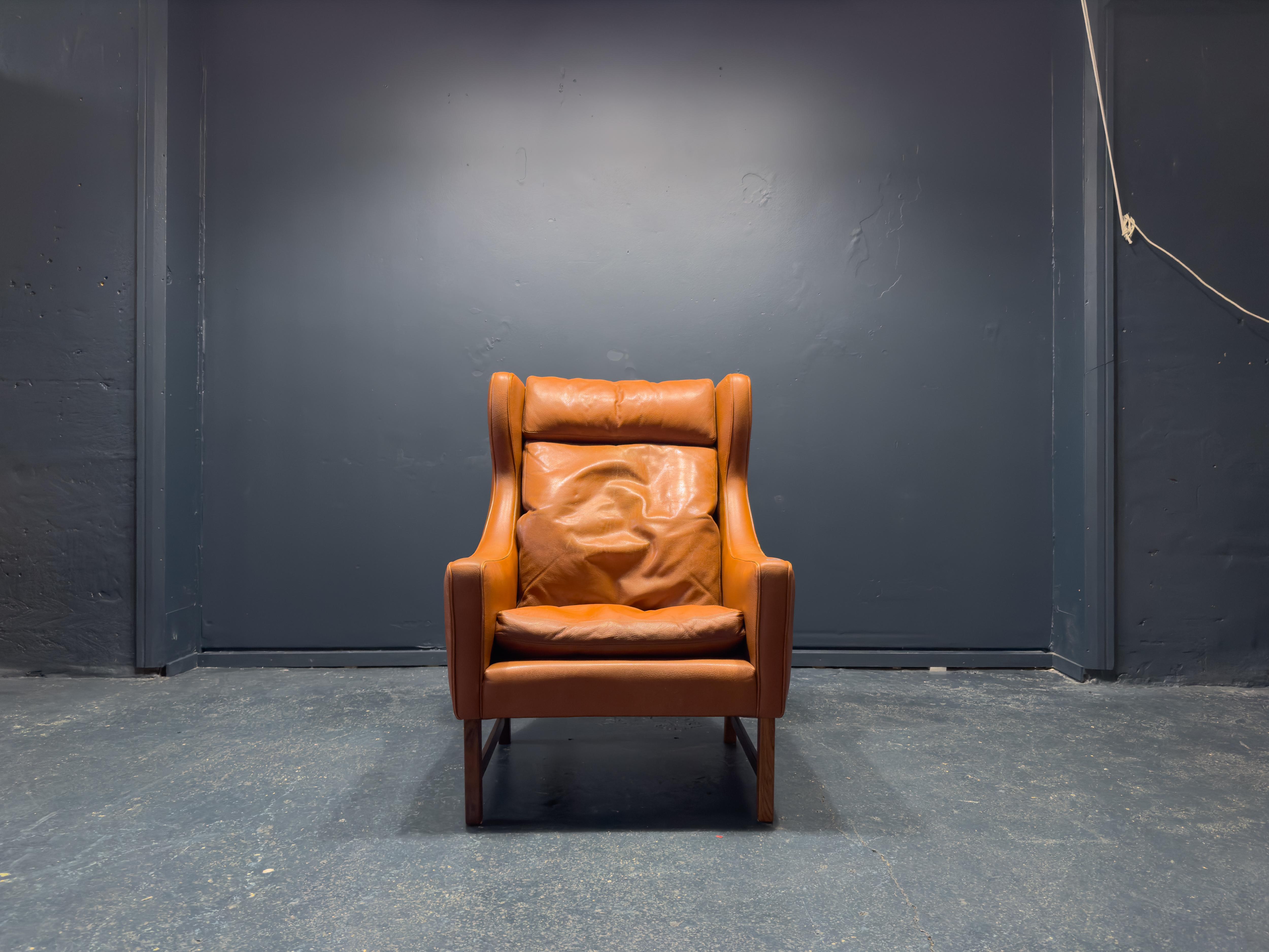 Created by Norwegian furniture designer Fredrik Kayser for Vatne Mobler in the 1960s, this wingback armchair is a classic piece of design. Upholstered in a stunning cognac-coloured leather with a rich patina and strong lines throughout the piece
