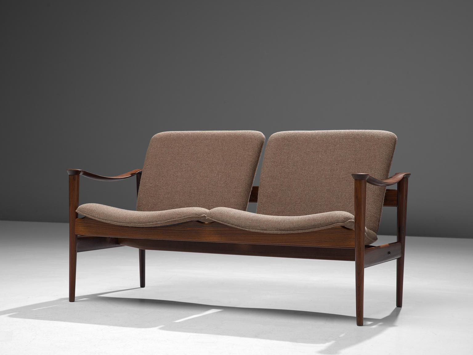 Fredrik A. Kayser for Vatne Lenestolfabrikk, model 711 sofa, rosewood and taupe/brown fabric, Norway, 1960.

This settee is designed by Frederik A. Kayser and executed by Vatne Lenestolfabrikk. The sofa is executed in rosewood, leather and are